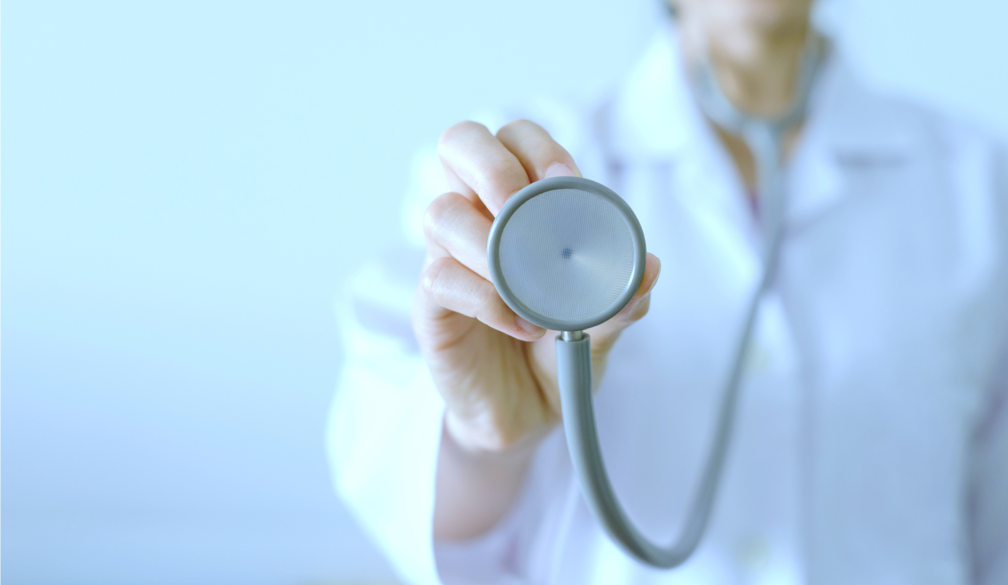 close up of female doctor standing and holding stethoscope for c