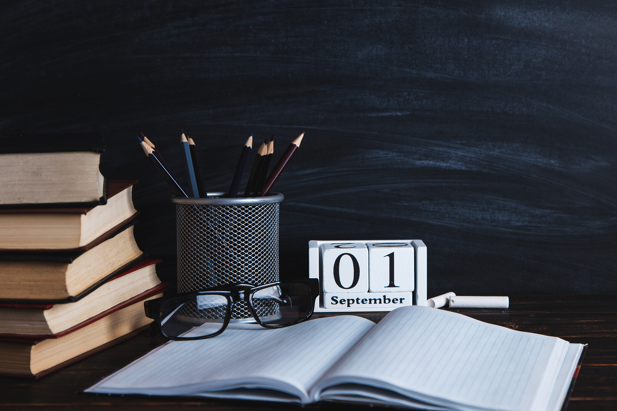 books, calendar, notebooks, pencils, glasses and a cup of coffee
