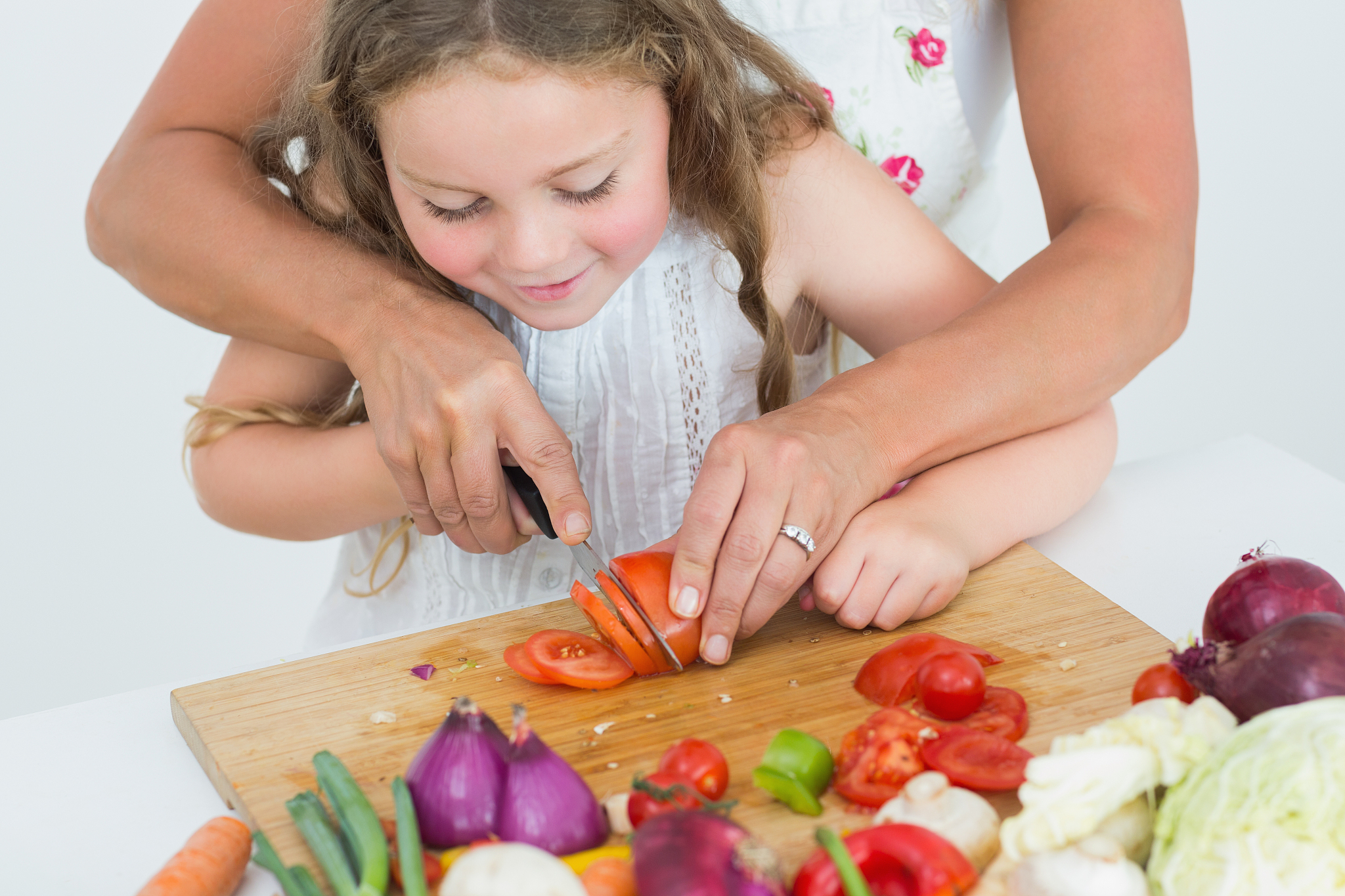 mother helping her daughter to cut tomato