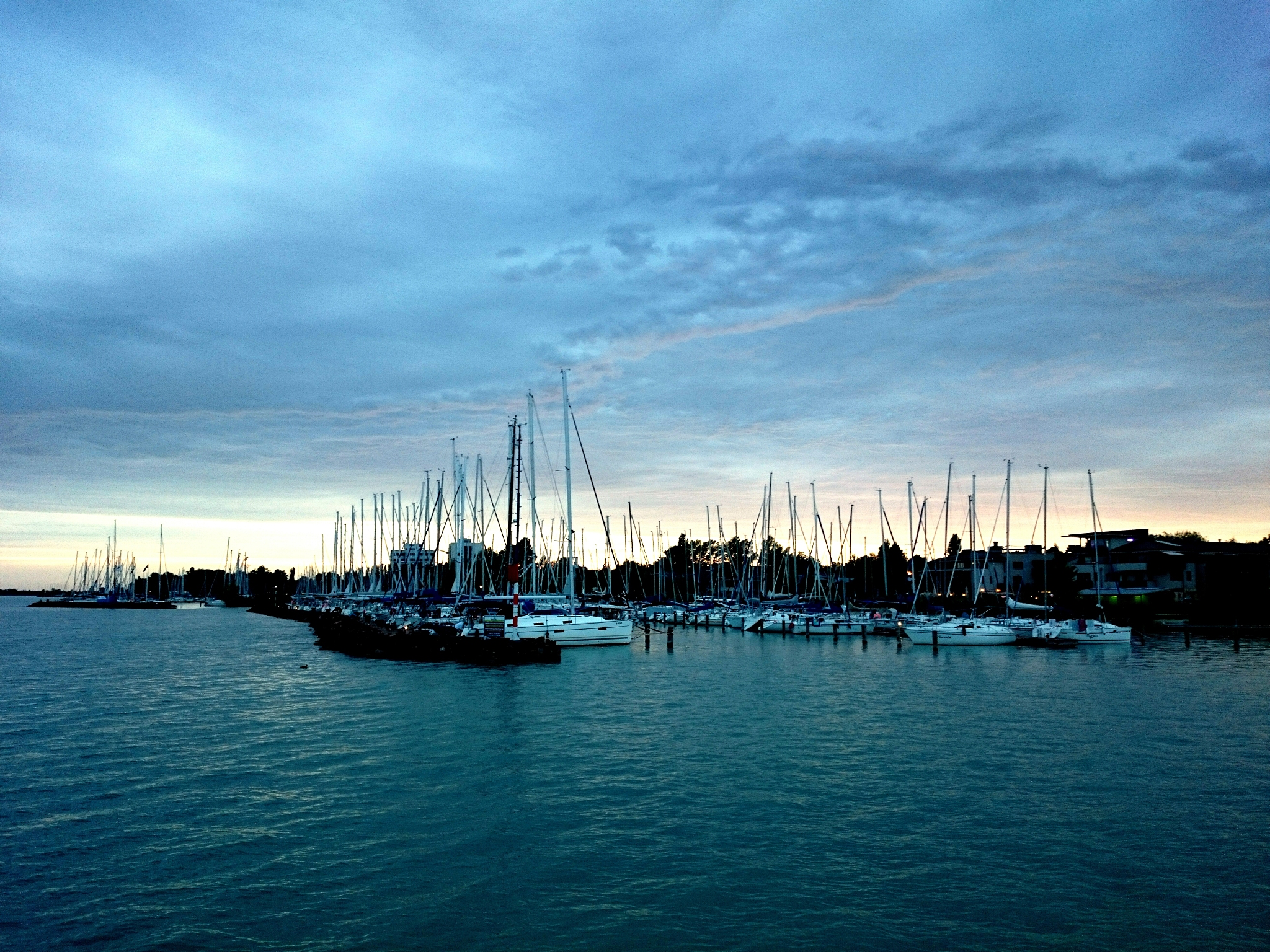 sailboats moored on lake balaton against cloudy sky