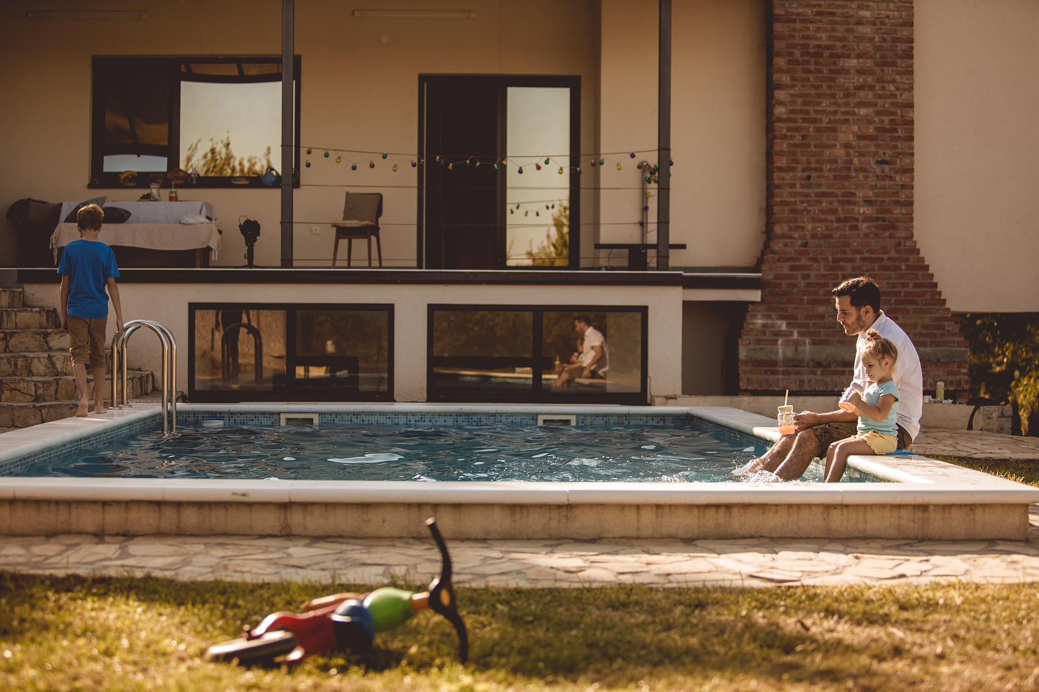 father and daughter relaxing their feet in the swimming pool whi