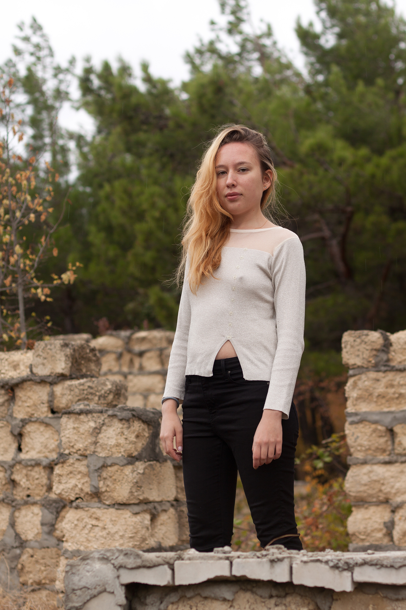beautiful girl stands on stone wall