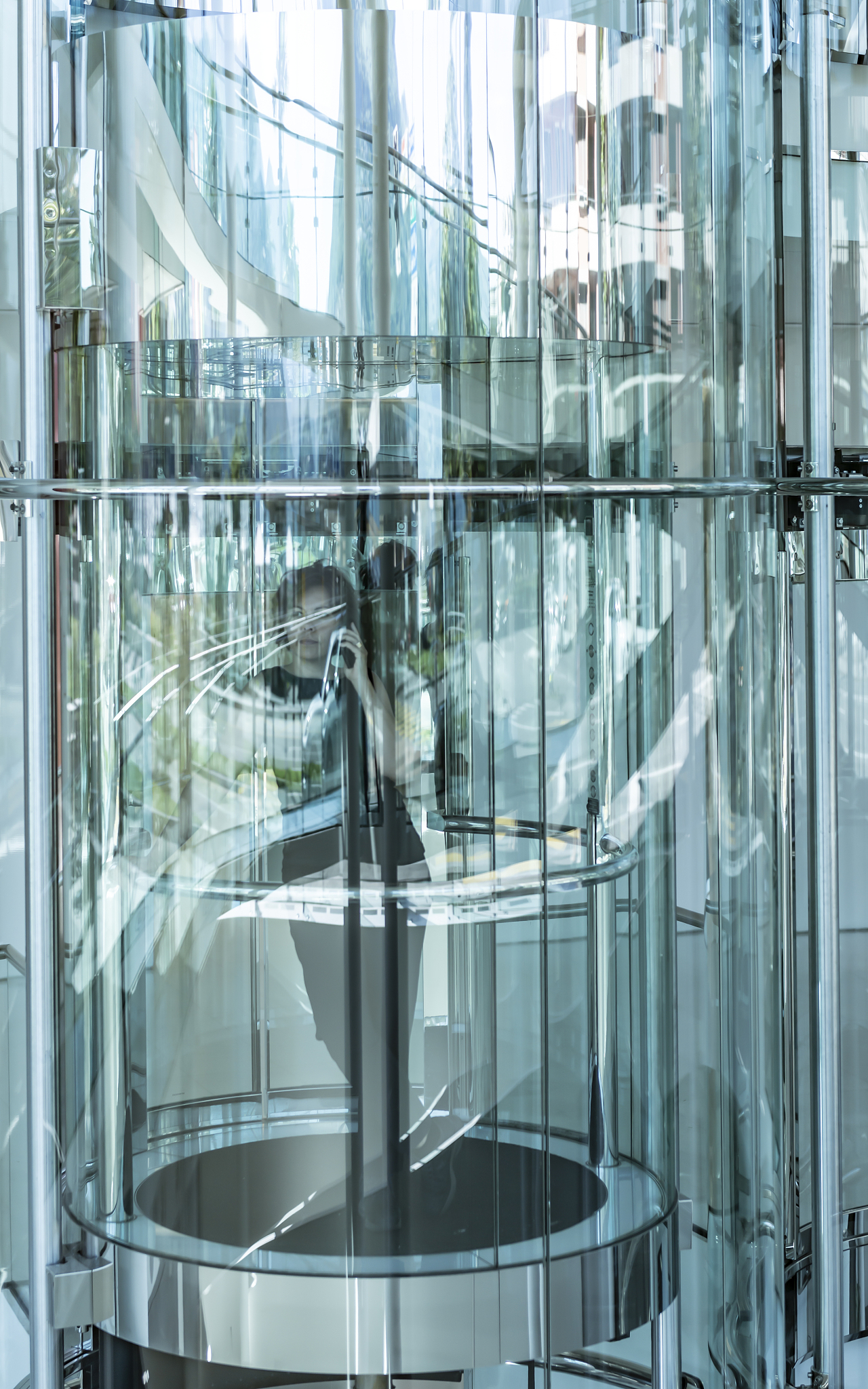 woman inside a modern glass elevator and using phone