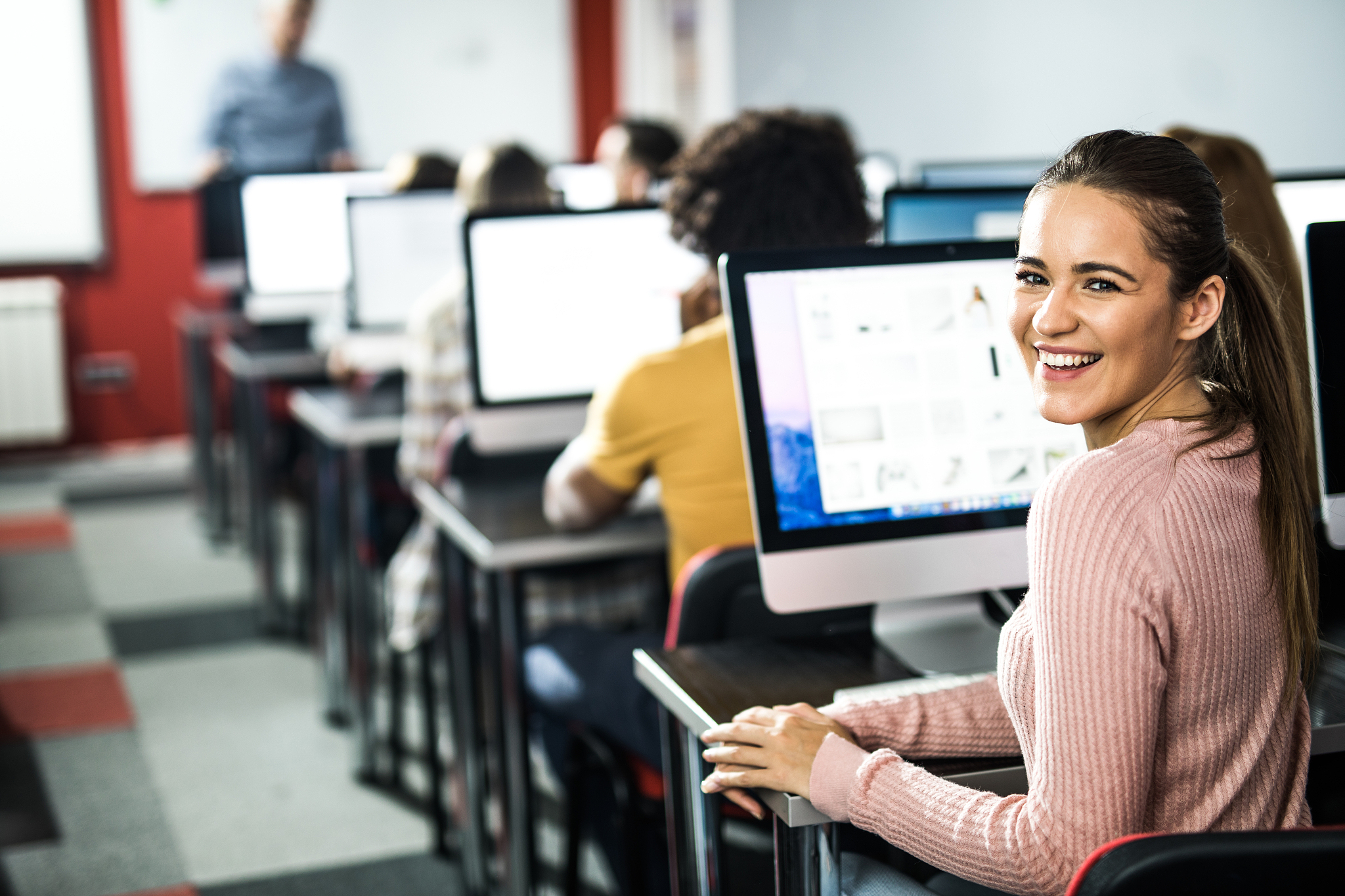 happy female student using pc during a class at computer lab.