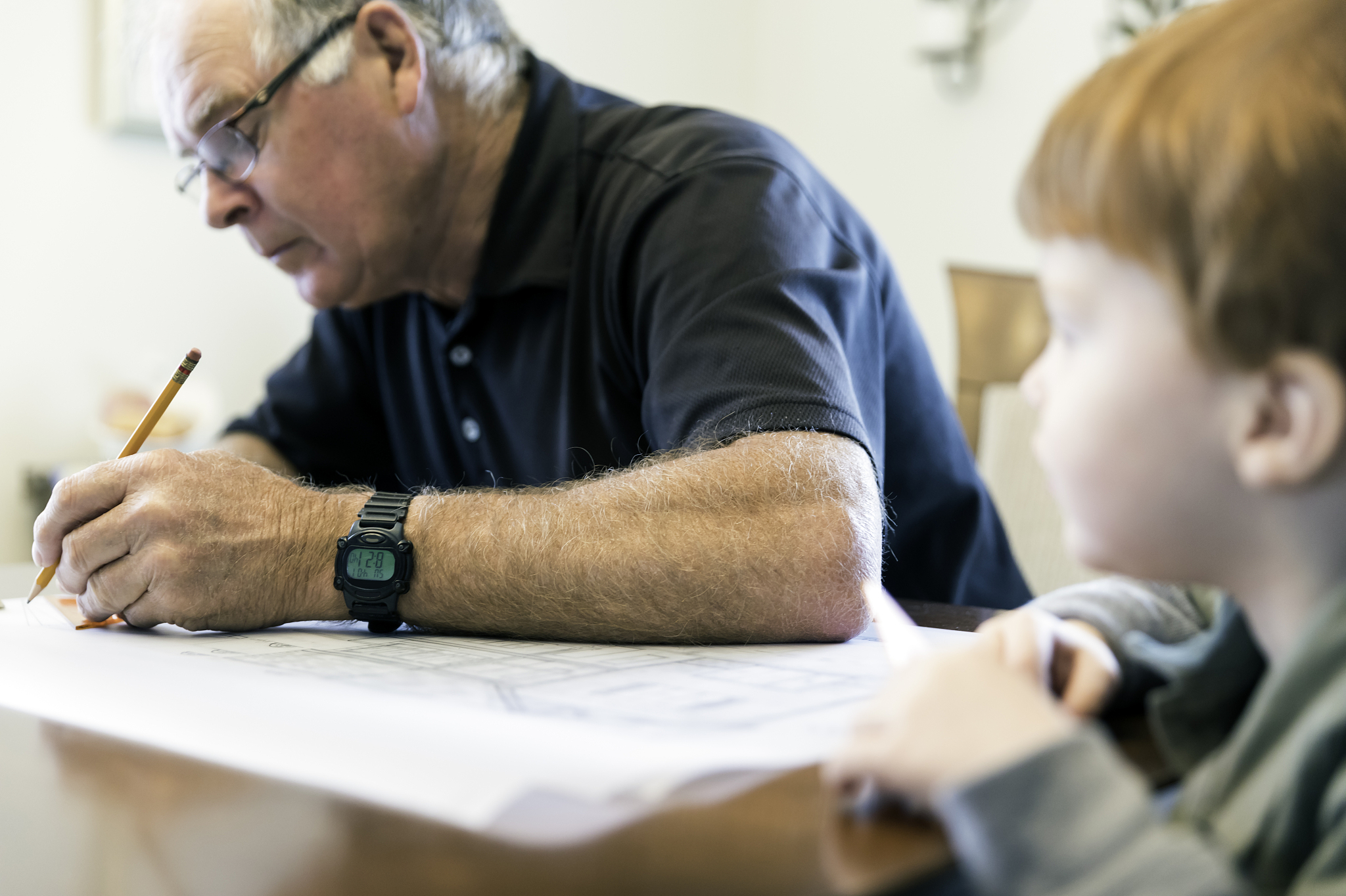 senior man drawing and looking at home plan design with grandson