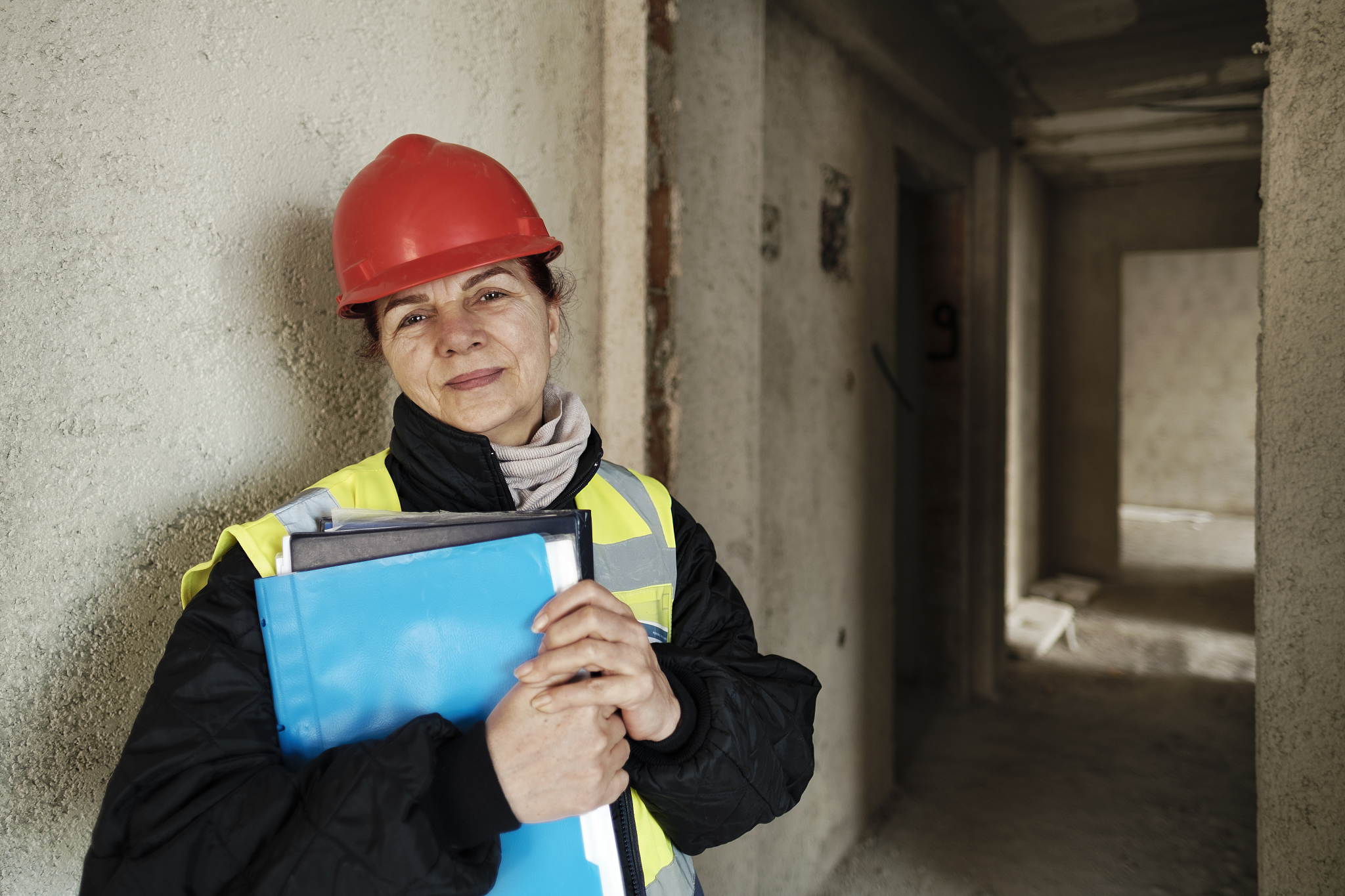 mature woman in red hard hat working at construction site.