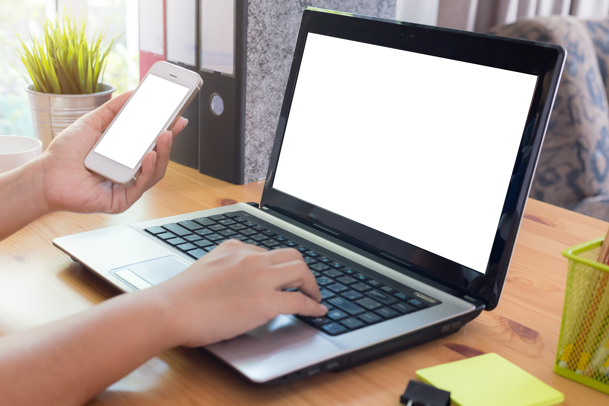 young woman working from home using smart phone and notebook com