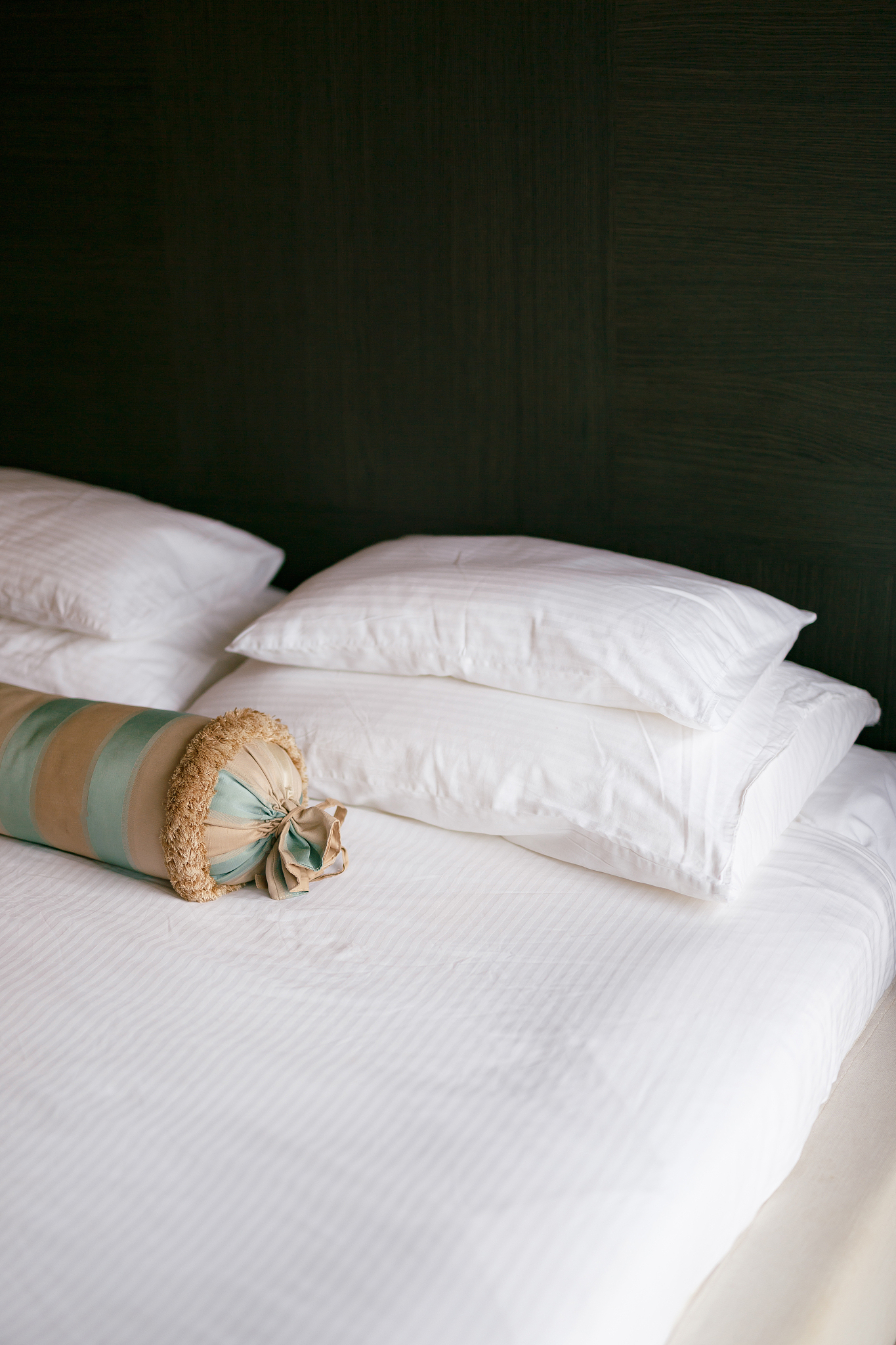 a bed with a white blanket and pillows of different sizes and an