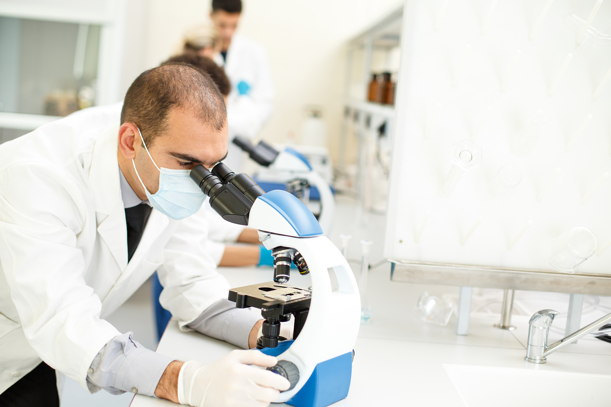 scientist looking through microscope