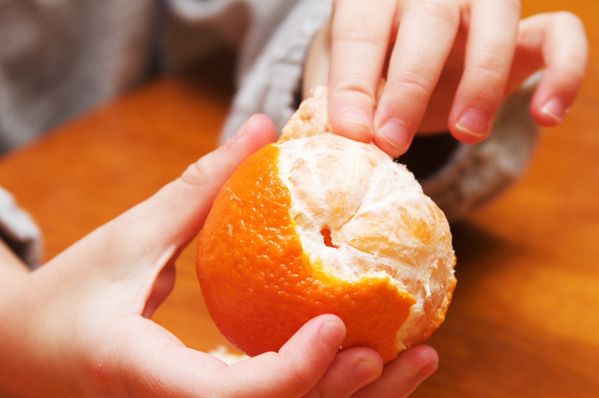 a young child peeling an orange