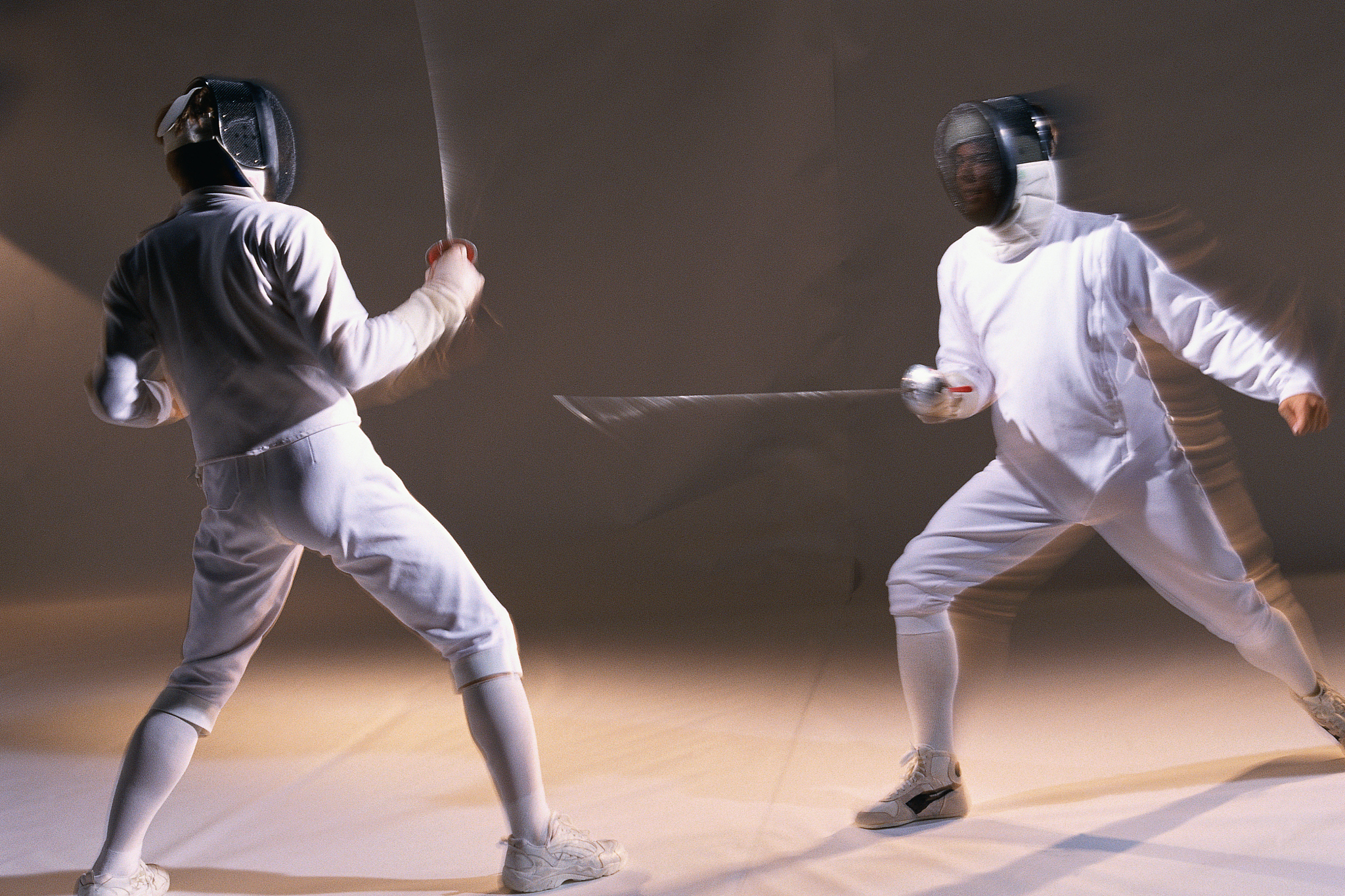 two fencers dueling, one attacking