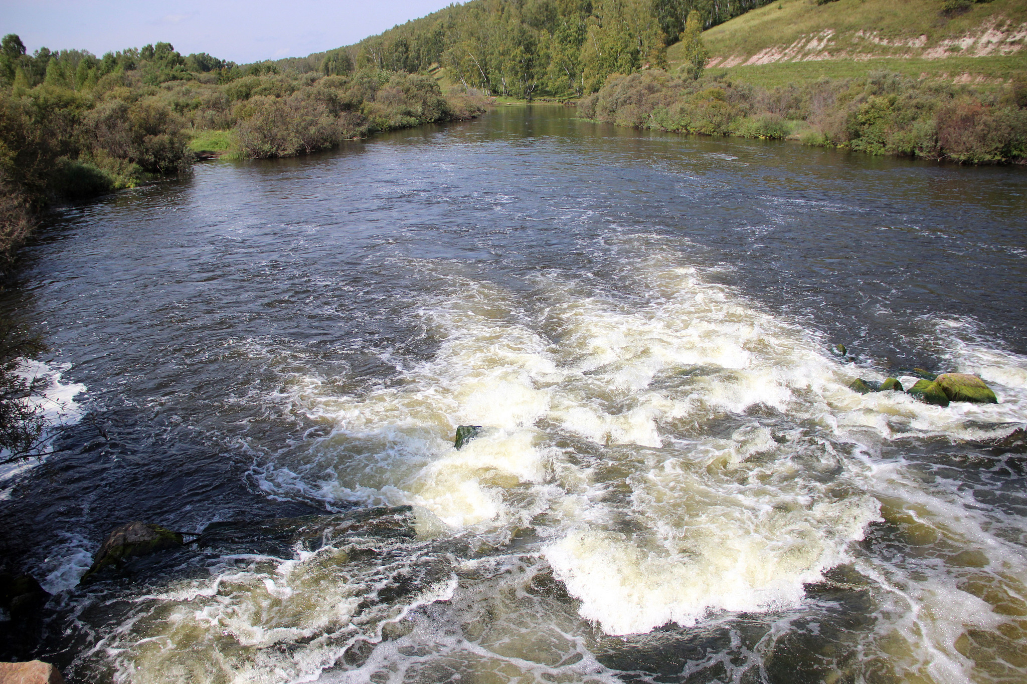 the mountain river flows over the rocks bubbling and foaming.