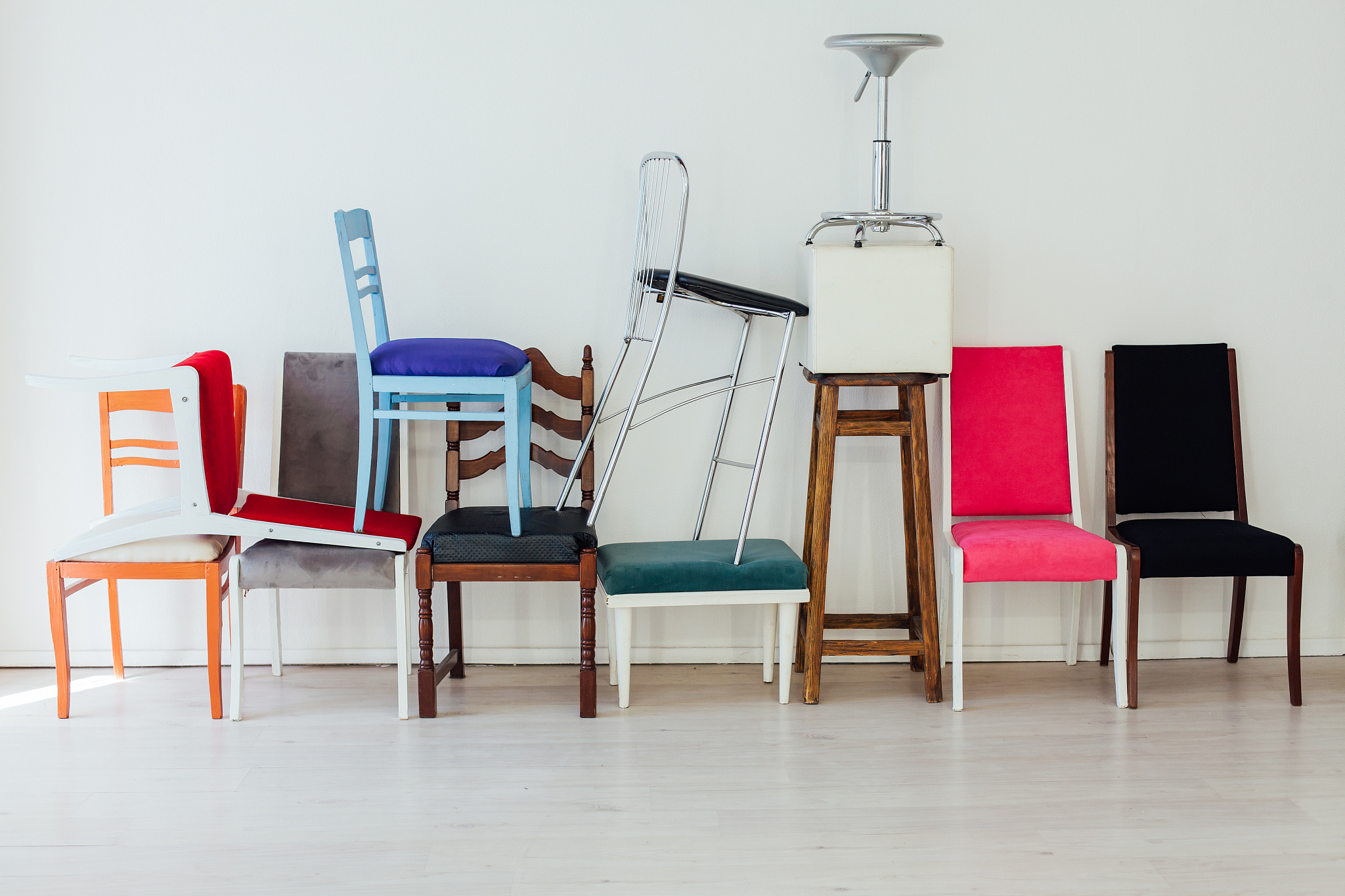 many different chairs stand in the white room