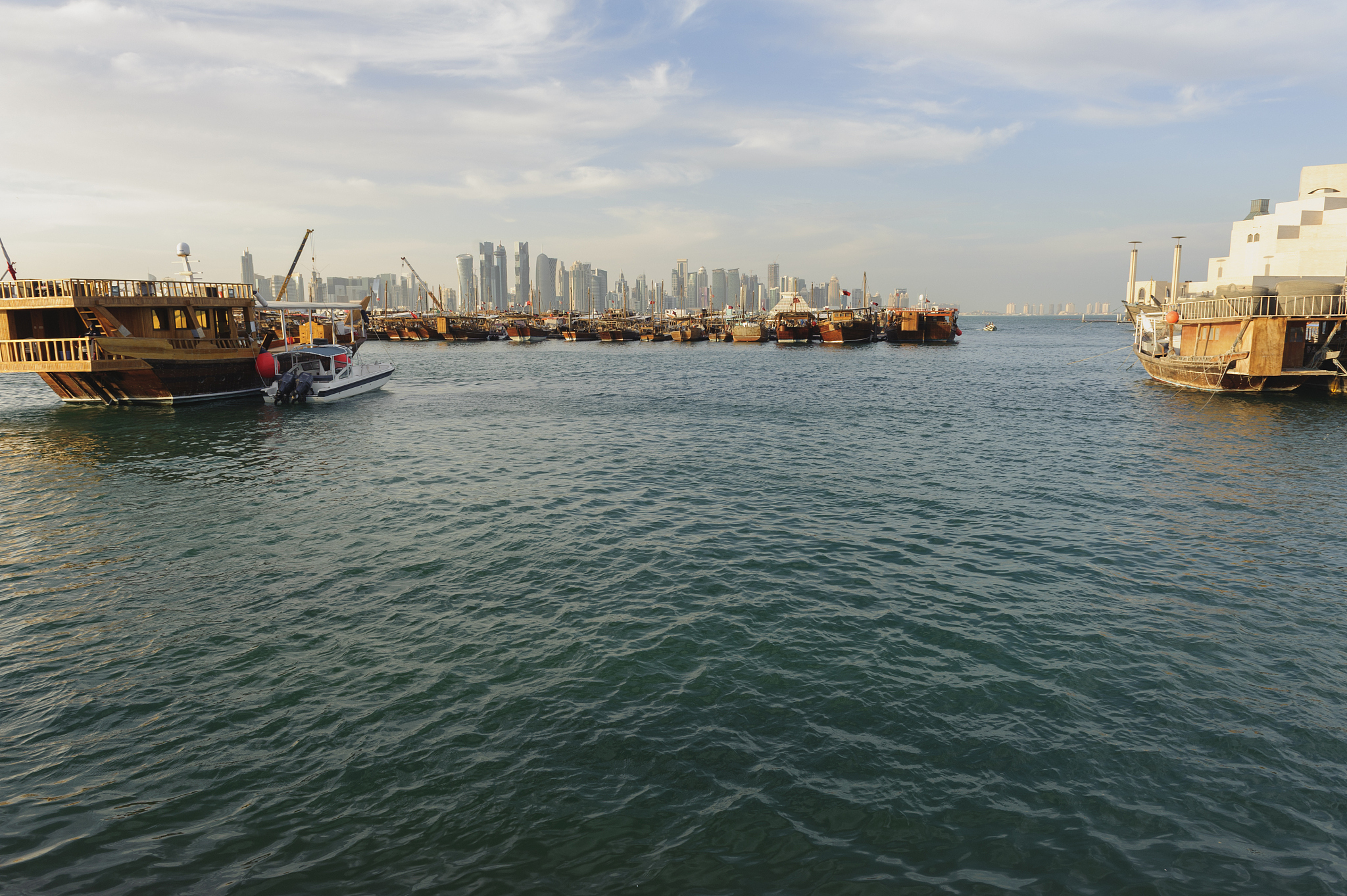 dhows in the harbor of doha, qatar at sunset