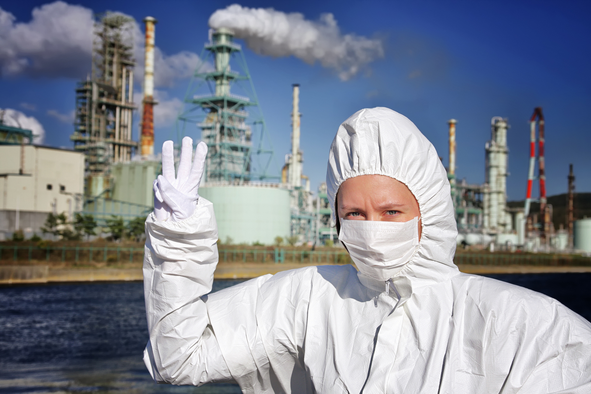 woman in the mask pointing number three with factory behind