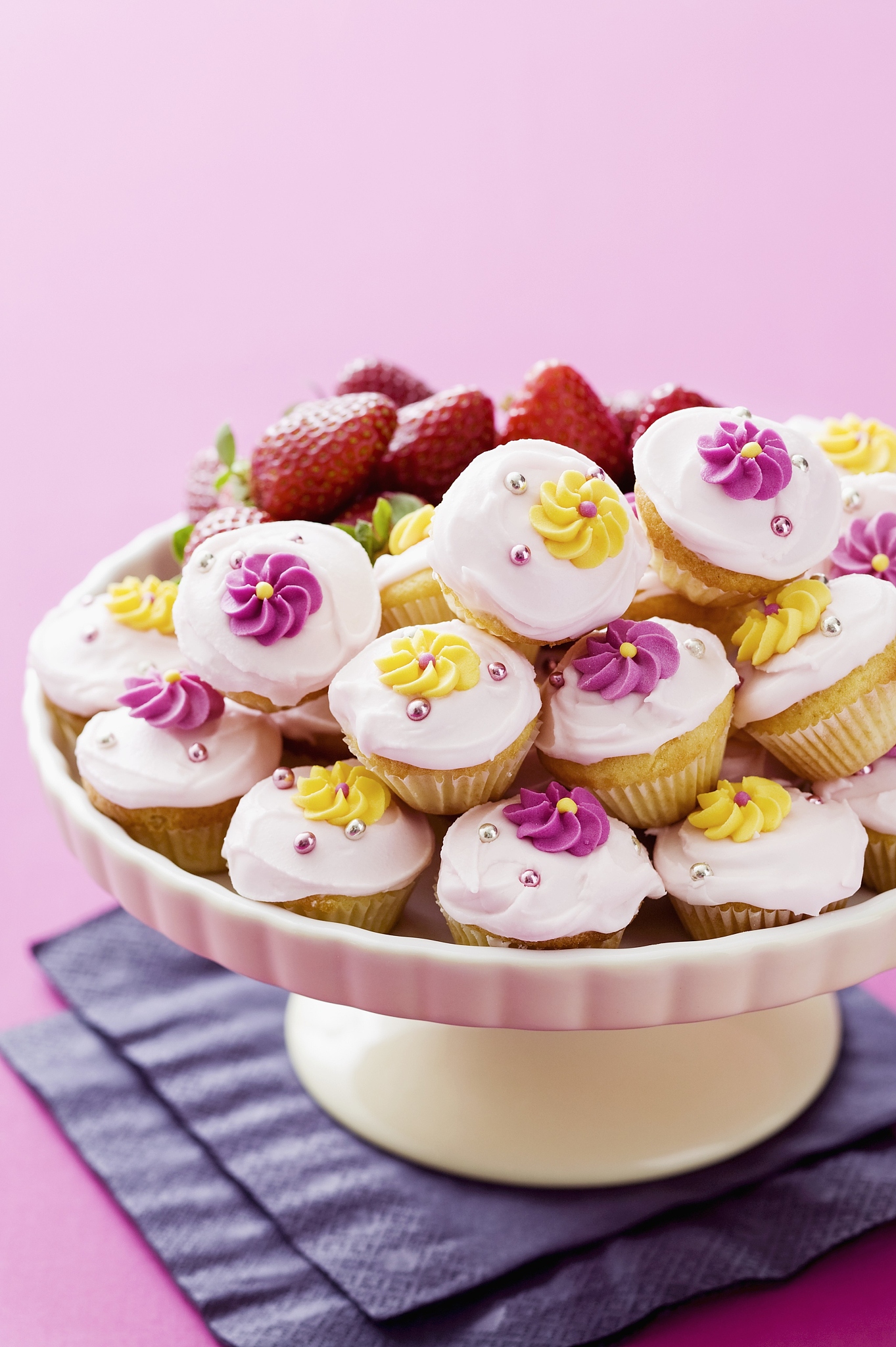lots of mini cupcakes decorated with sugar flowers, on a cake st
