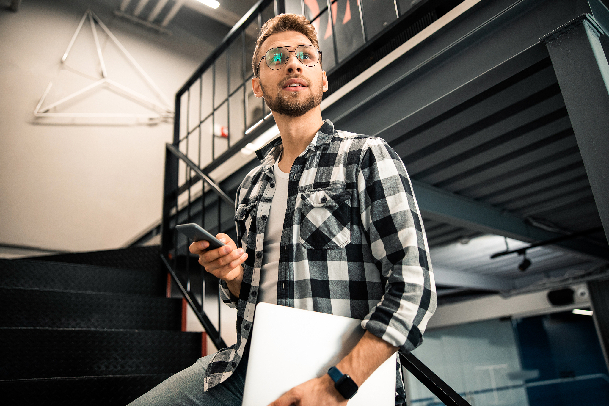 young guy holding smartphone and looking away