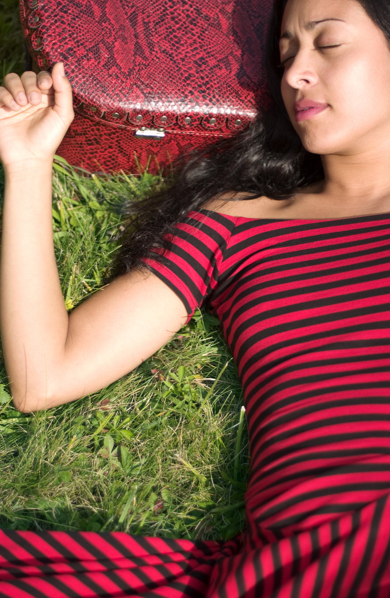 woman with suitcase lying down in field
