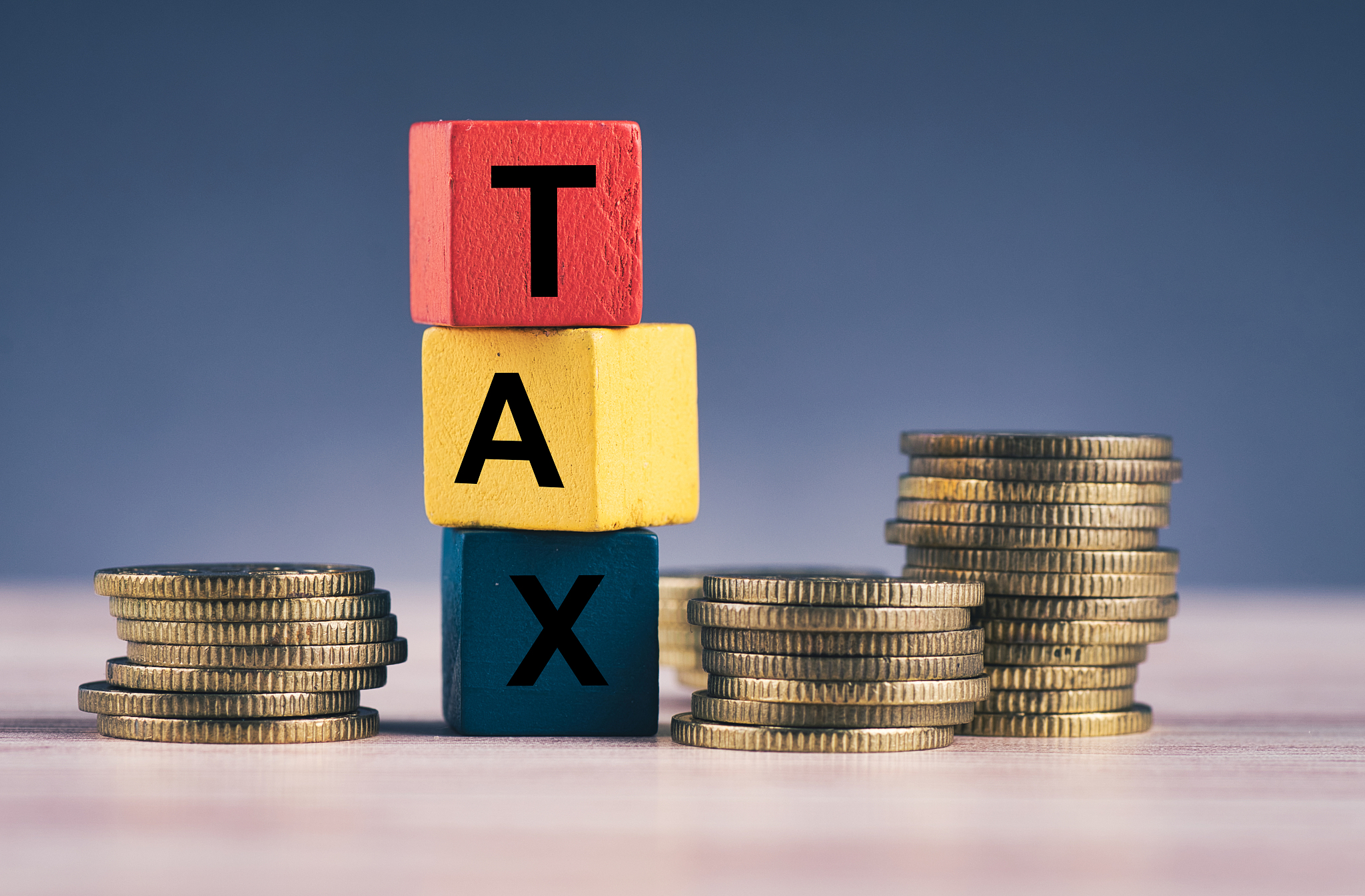 wood cube with word tax and stacking coin on wooden table