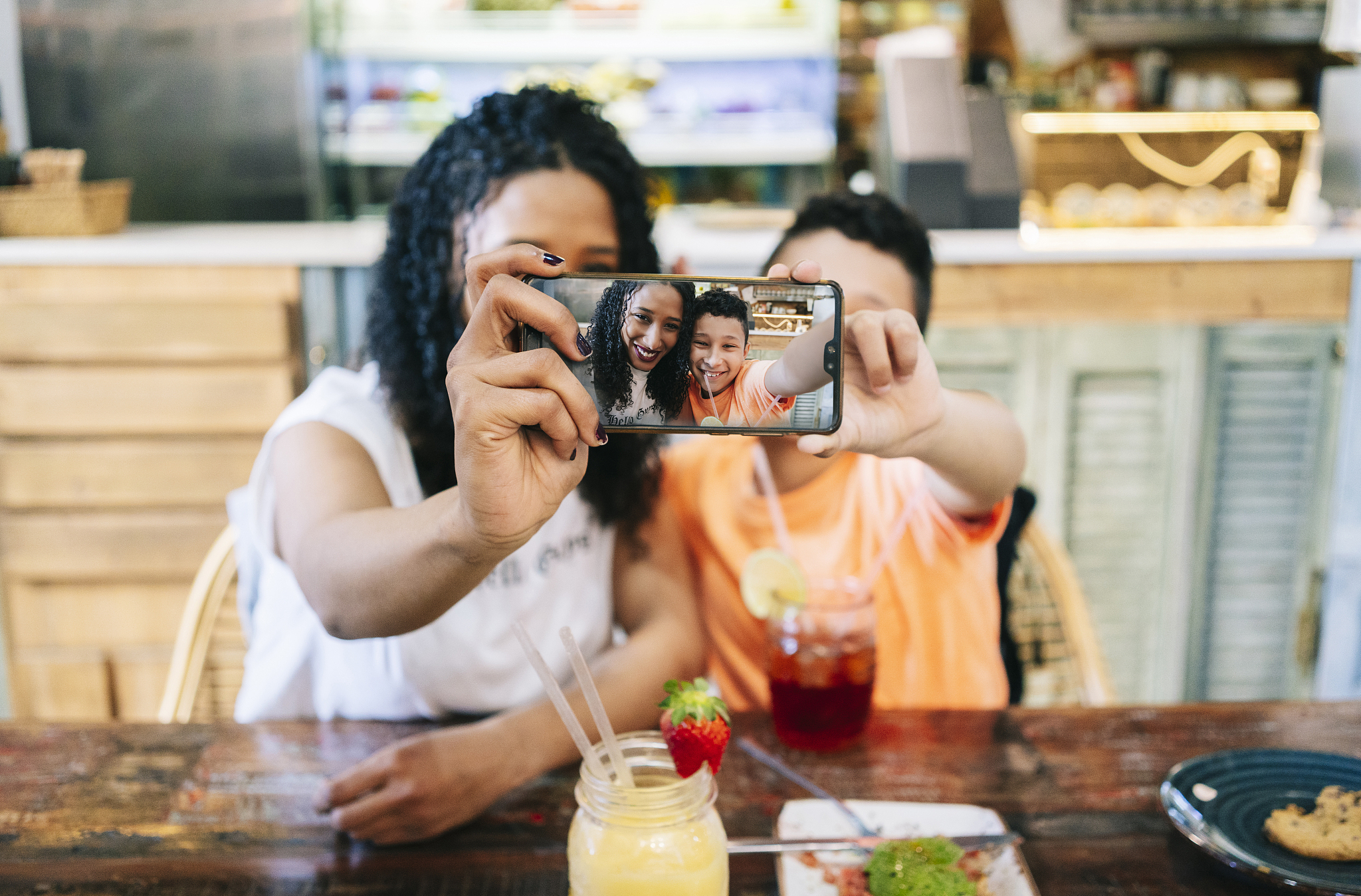 smiling mother and son taking selfie at restaurant