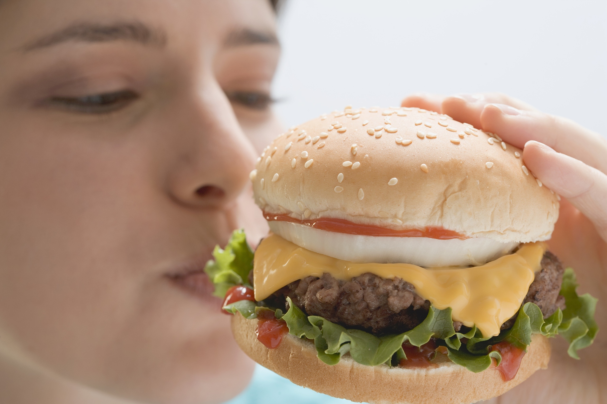 young woman biting into cheeseburger