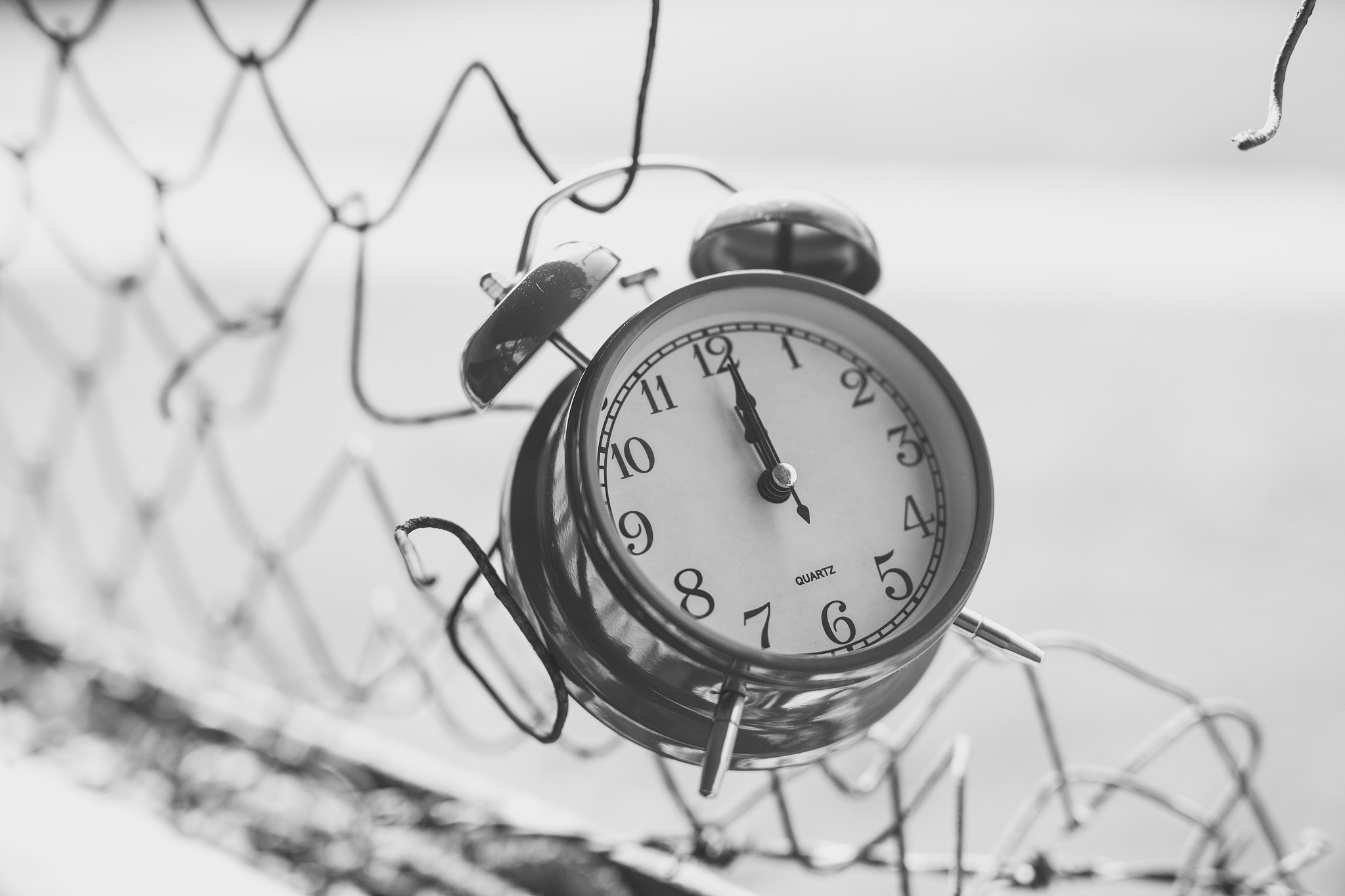 alarm clock hanging on metal fence