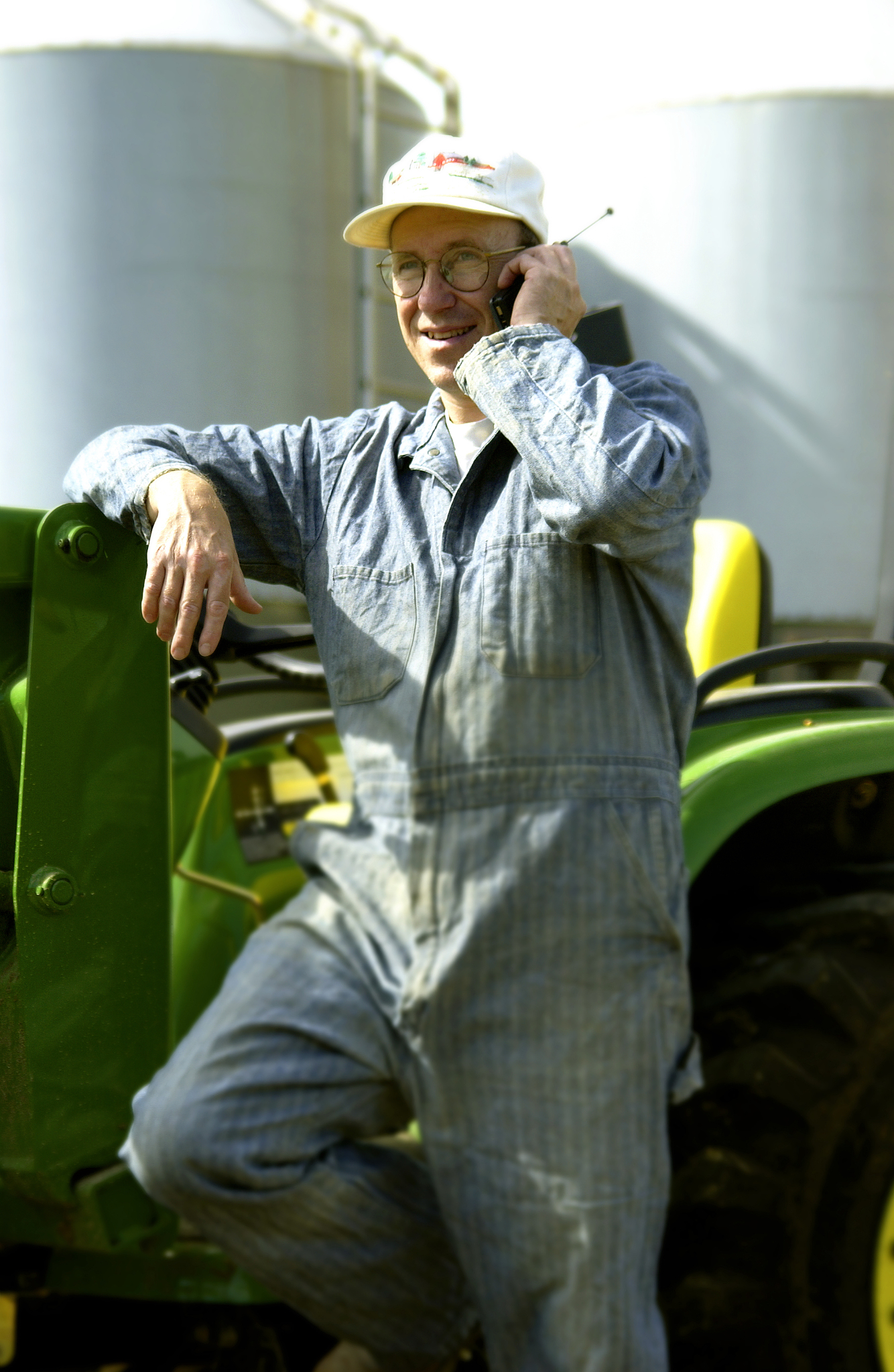 man leaning against tractor talking on cell phone