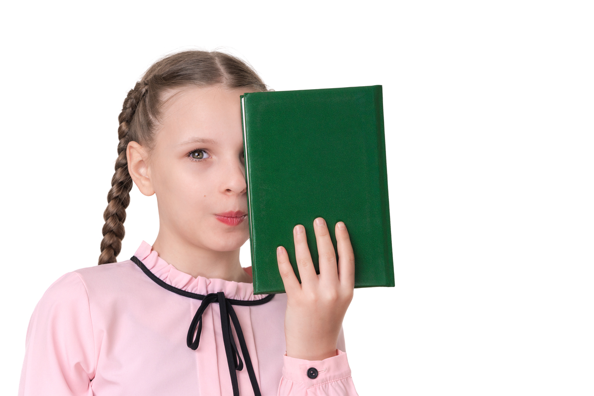 留着辫子的小学女生藏在一本绿皮书后面