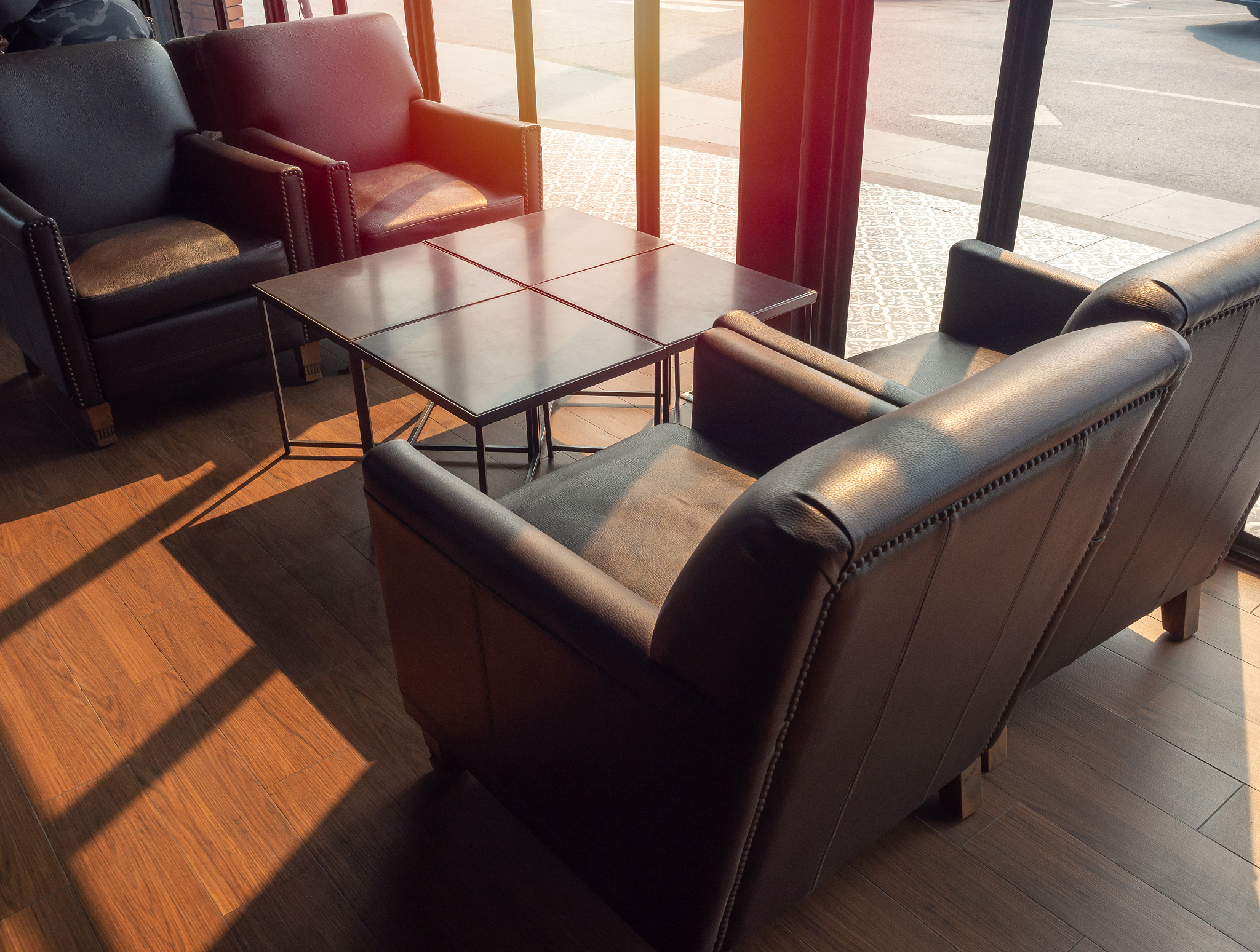 brown leather sofa with wooden table on wooden floor near glass 