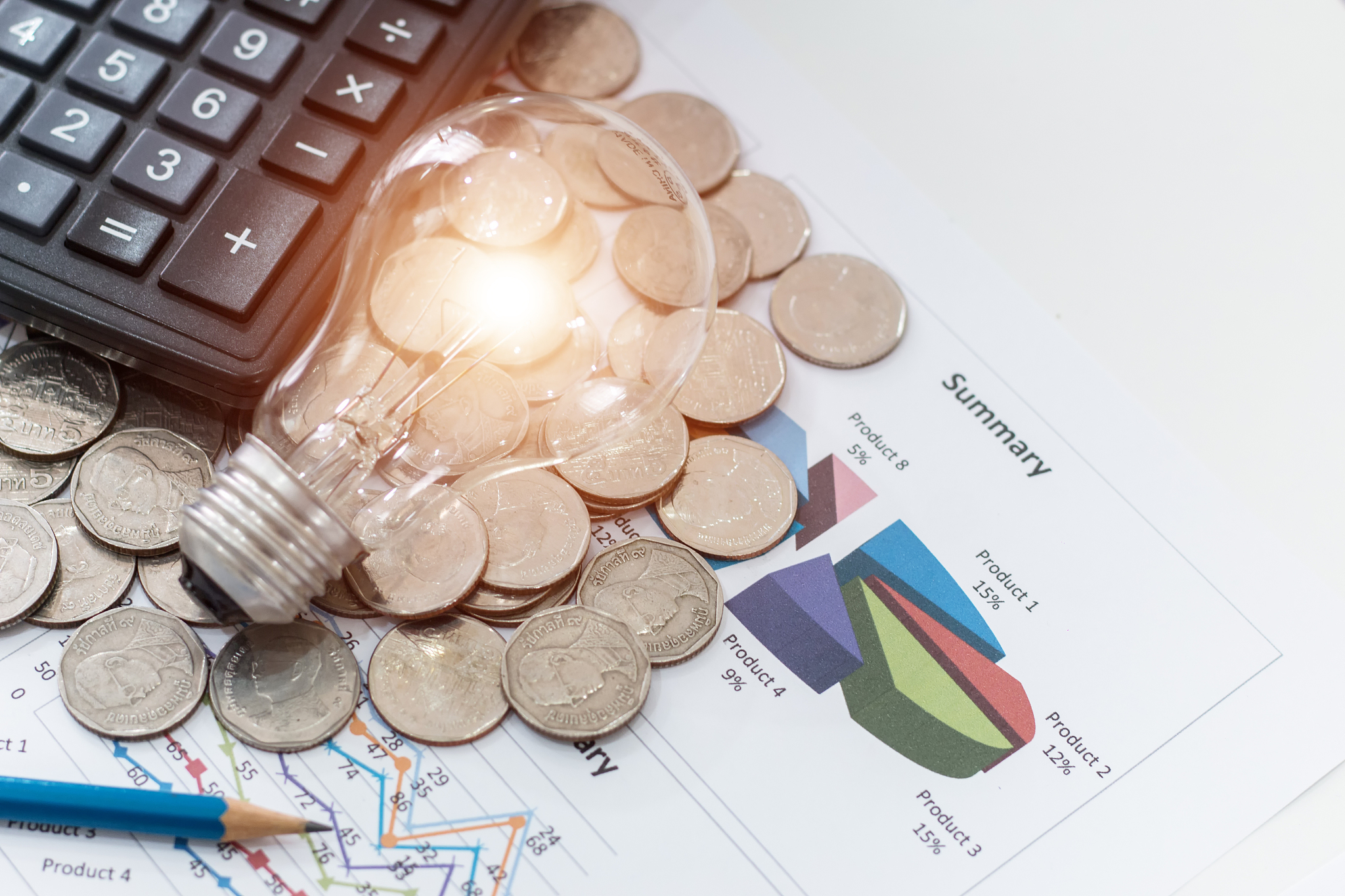 light bulb with coins and calculator on documents