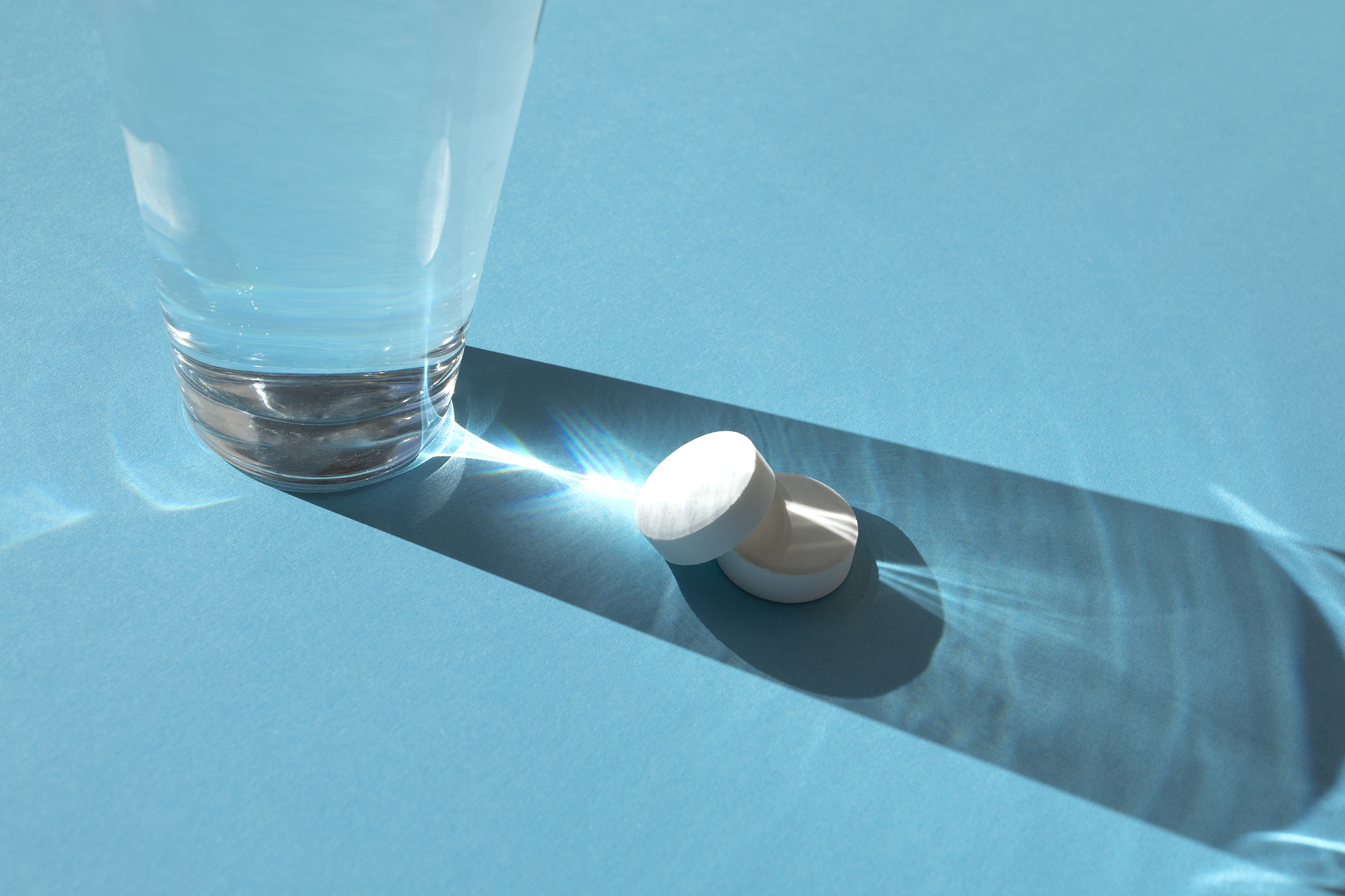 glass with effervescent tablets on the blue background