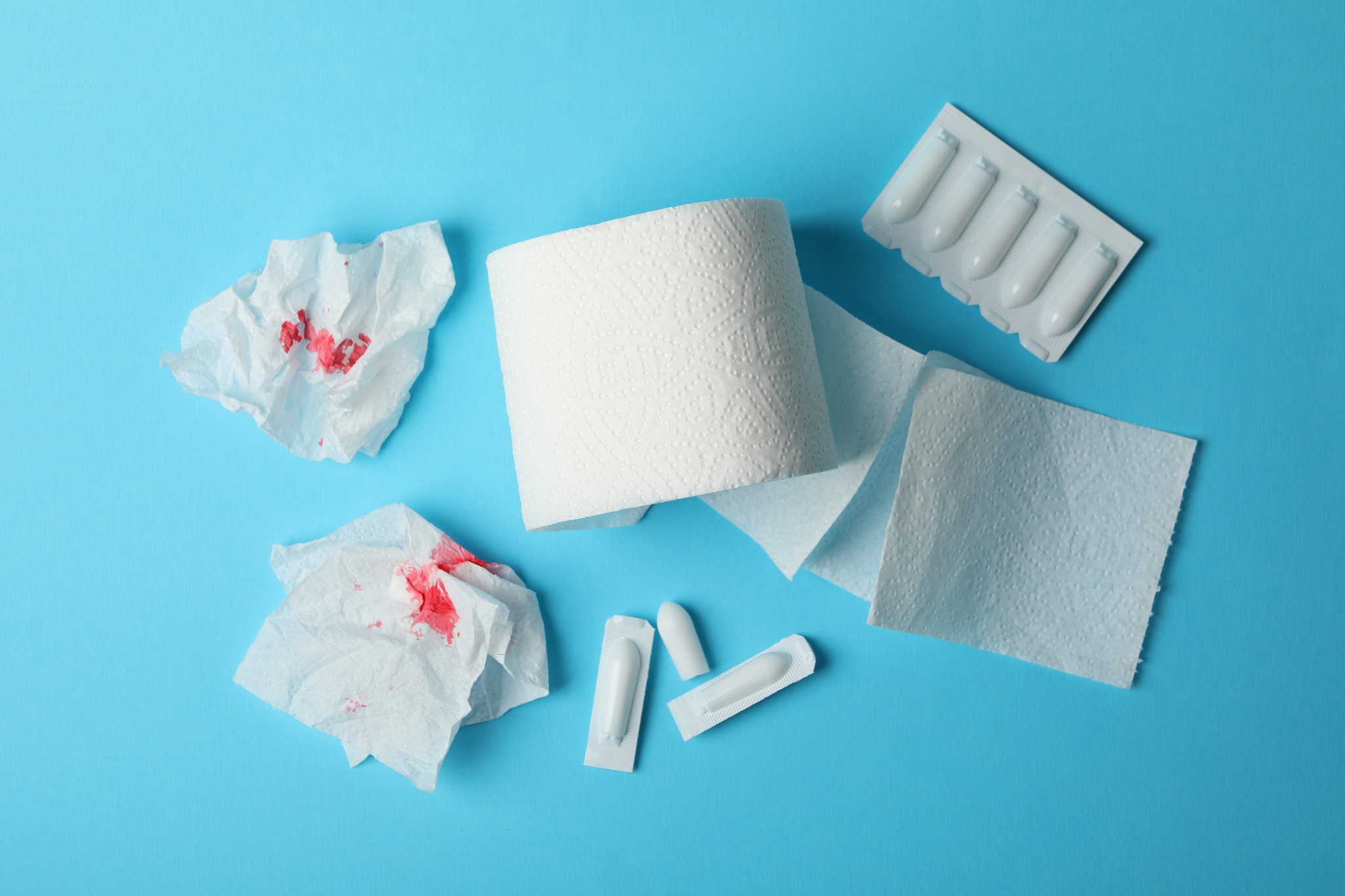 toilet paper, candles and paper with blood on blue background, t
