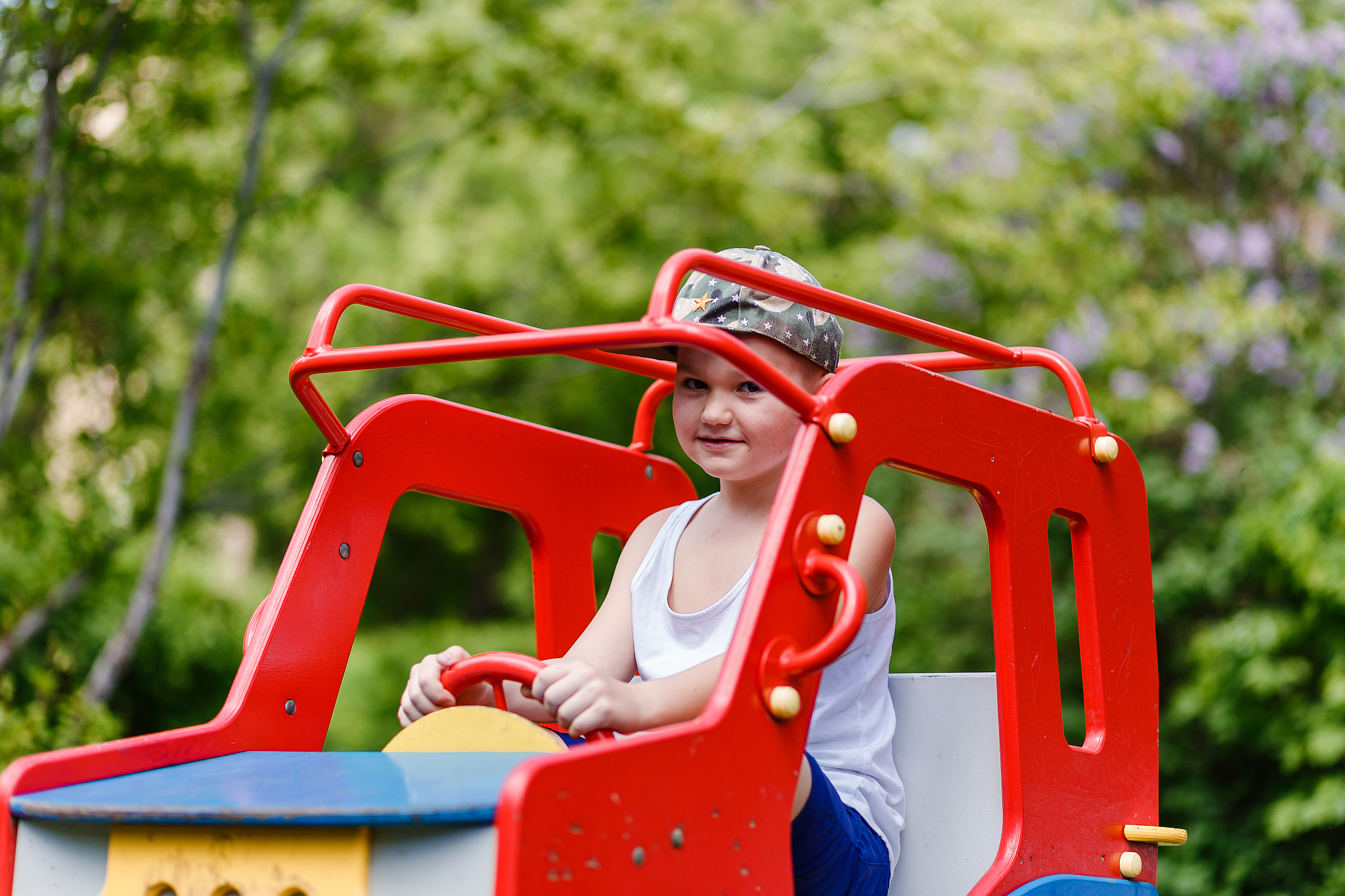 a seven-year-old boy sits on a wooden children's car in the summ