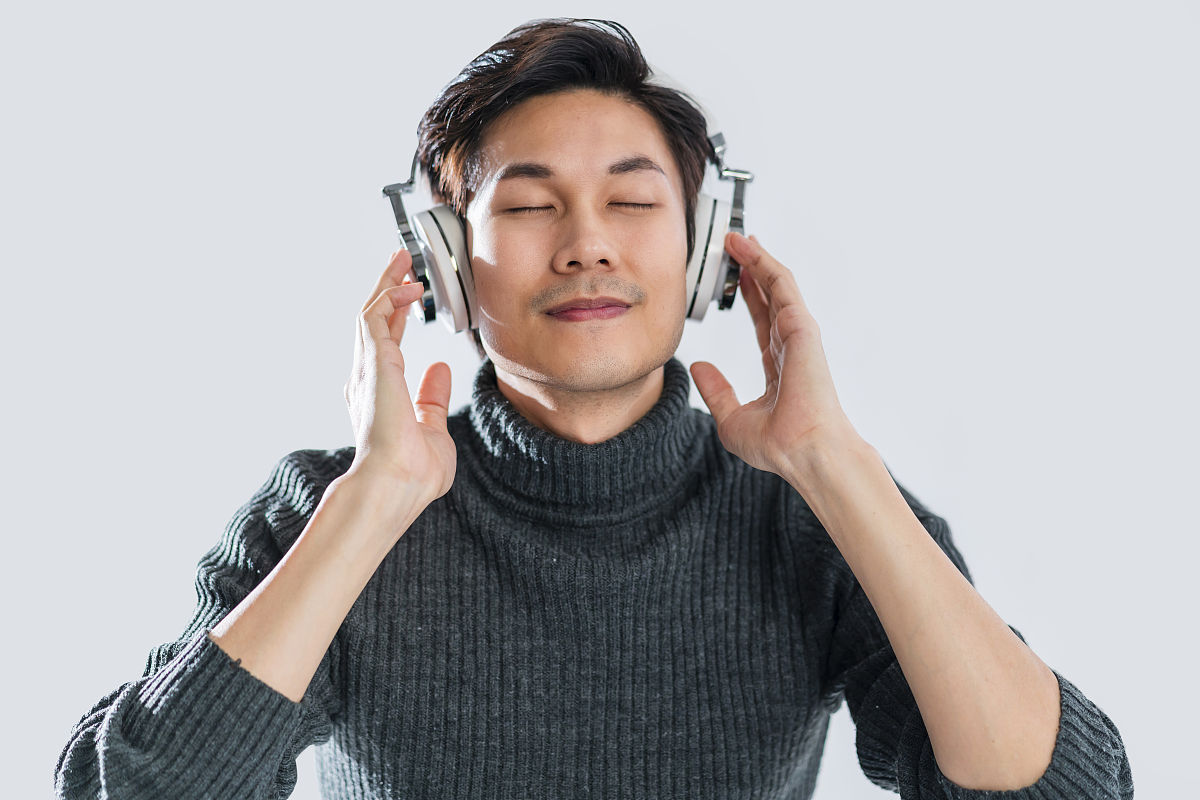 人像工作室音乐歌词概念年轻聪明的亚洲艺术家穿毛衣听耳机享受音乐音