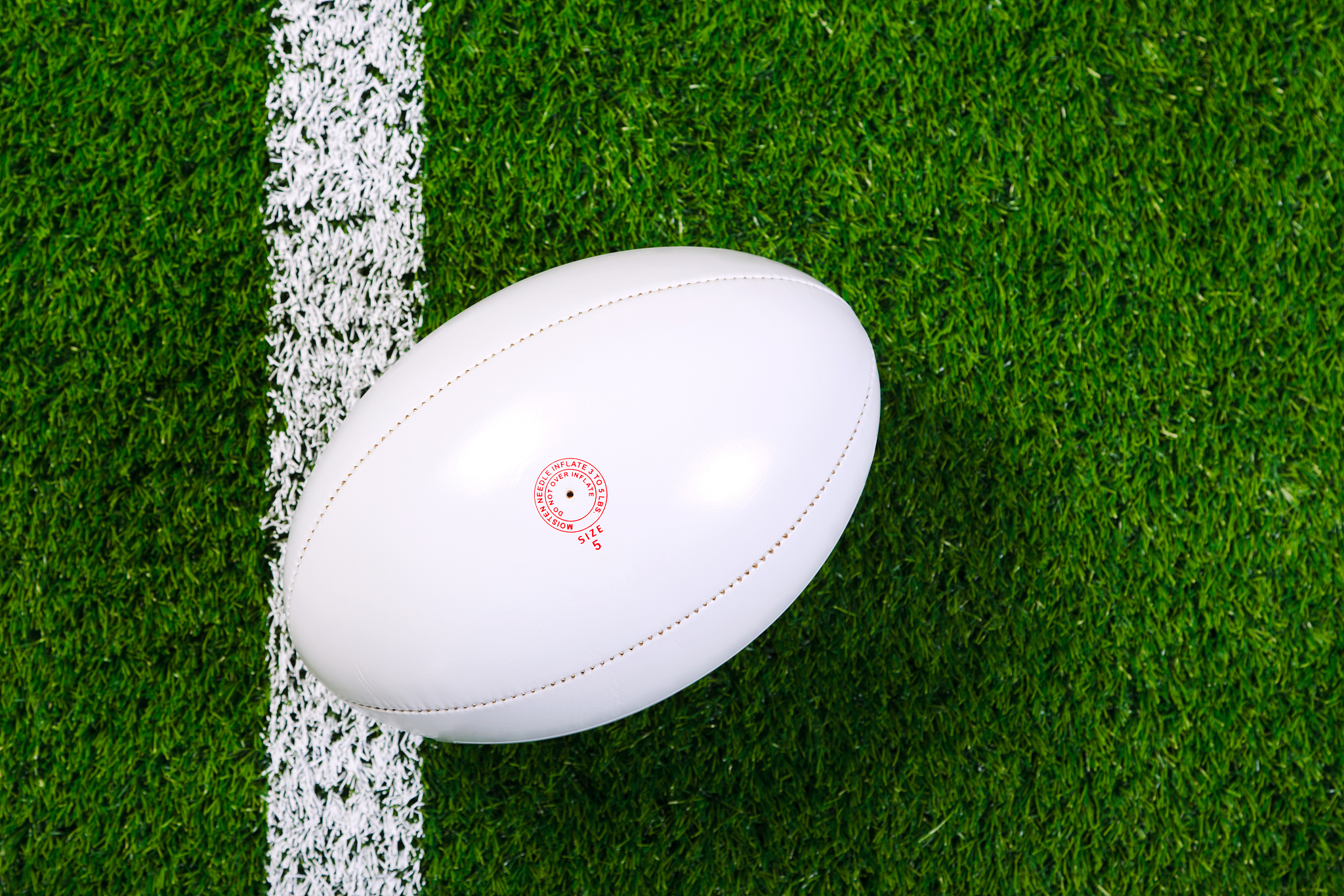 white rugby ball in a grass field shot from above