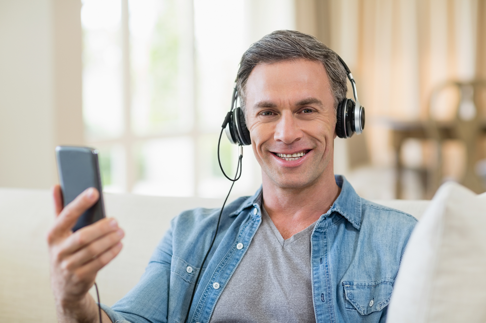 man listening to music on headphones in living room at home
