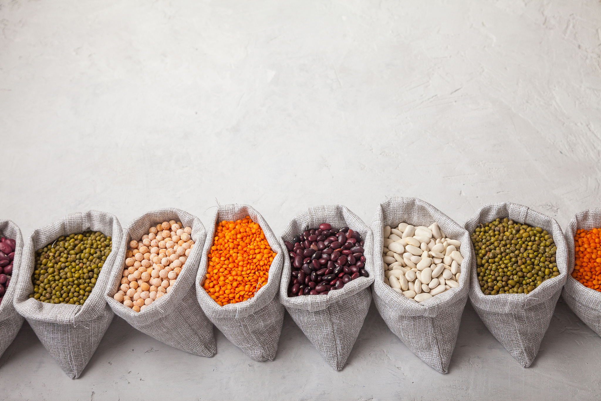 beans, lentils, peas, soybeans in bags on a white background. ke