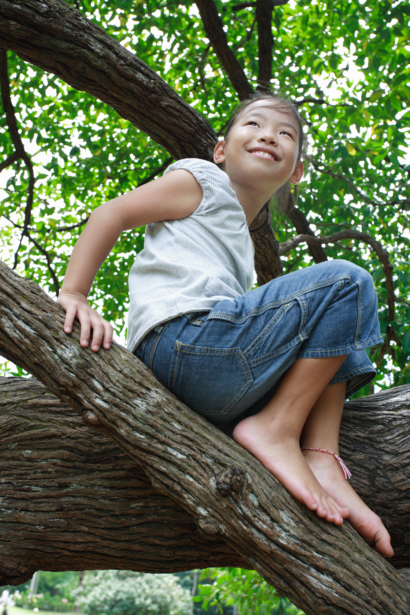 low angle view of a girl sitting on a tree and smiling