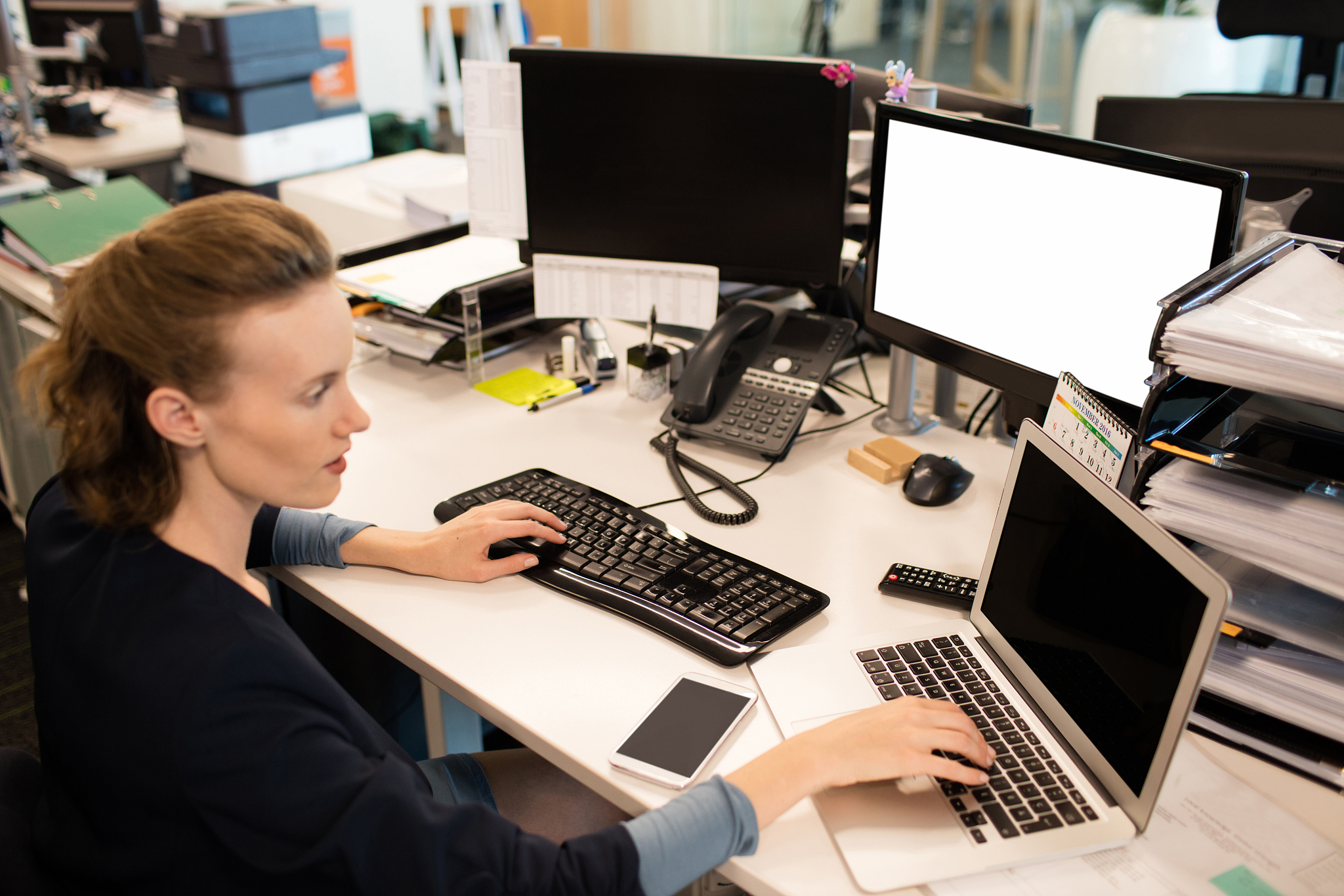 businesswoman typing on laptop while using desktop pc