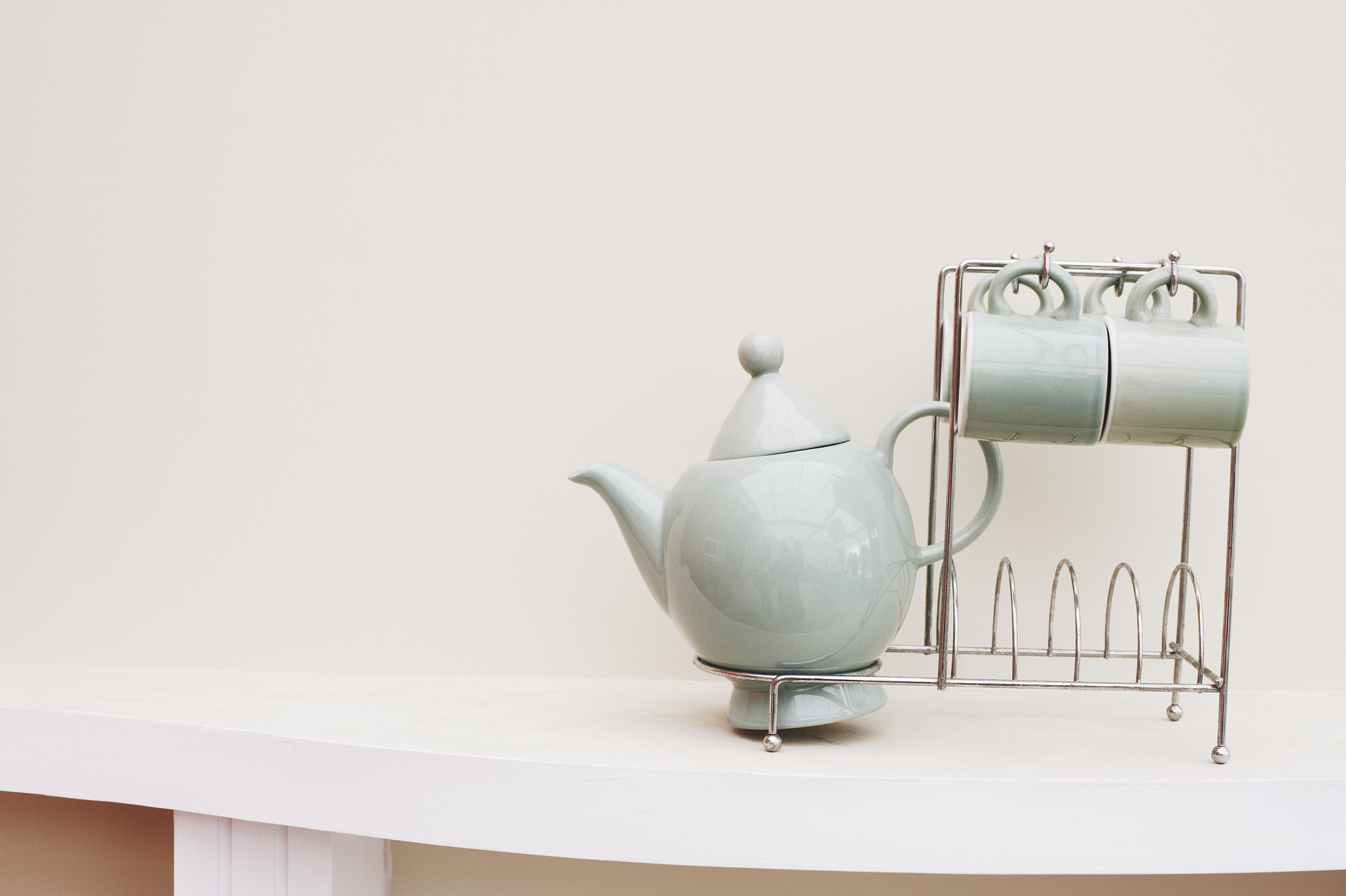 close-up of a tea cup and a tea kettle on a rack