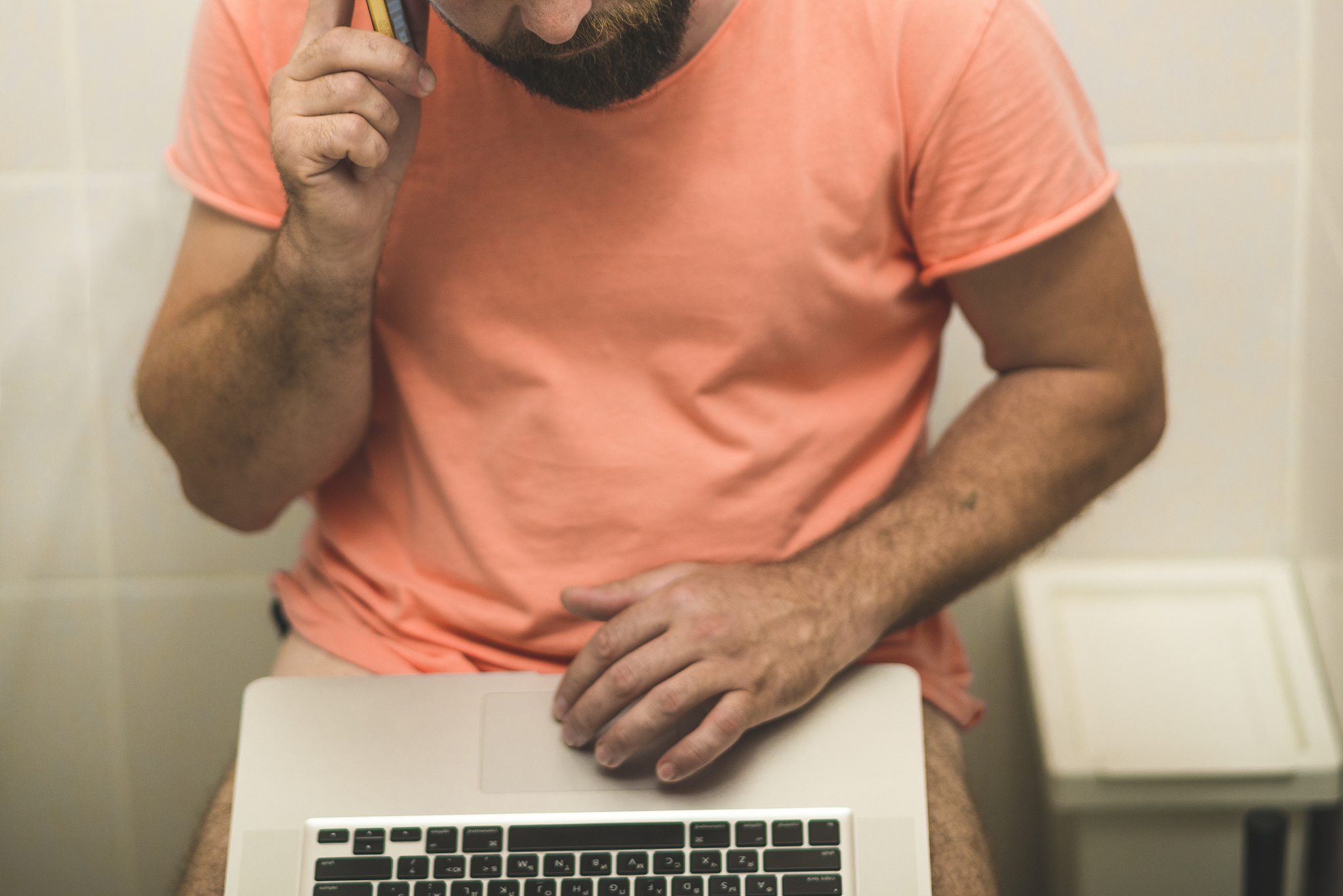 businessman is working with laptop while sitting on the toilet