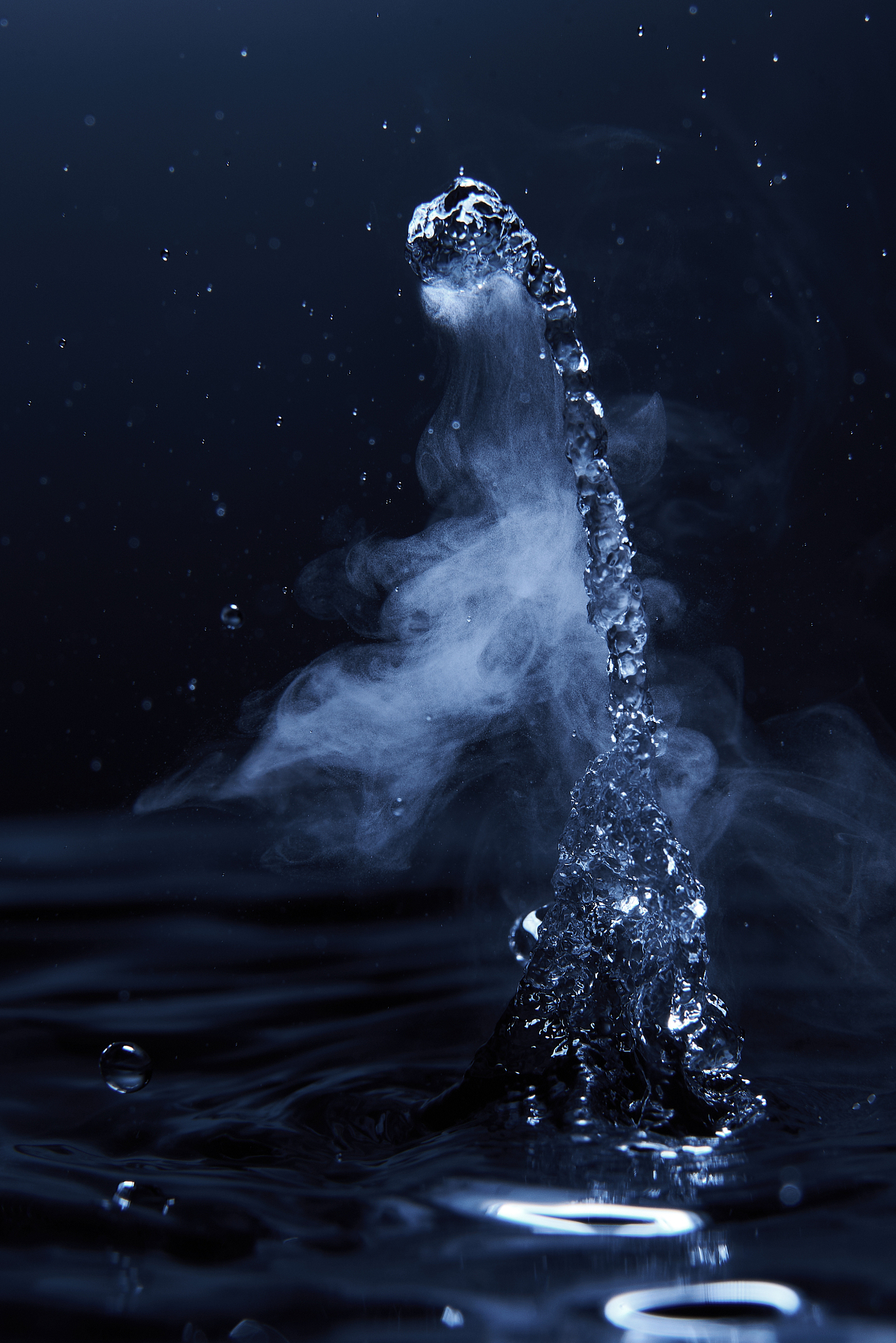 boiling water splash with steam on dark blue background closeup
