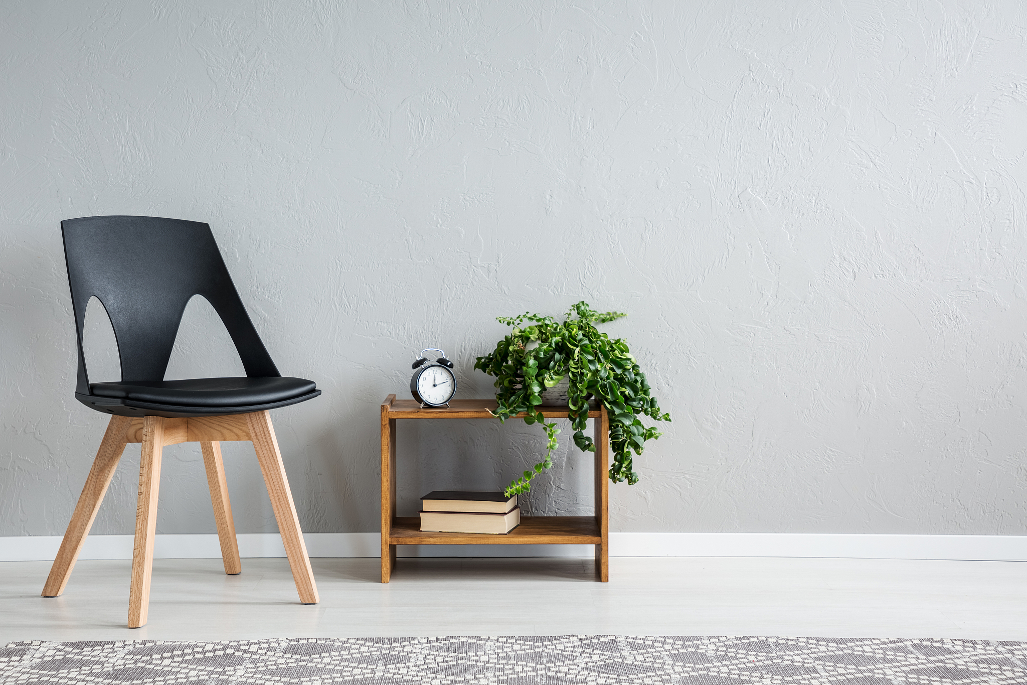 stylish black chair next to shelf with two books, clock and gree
