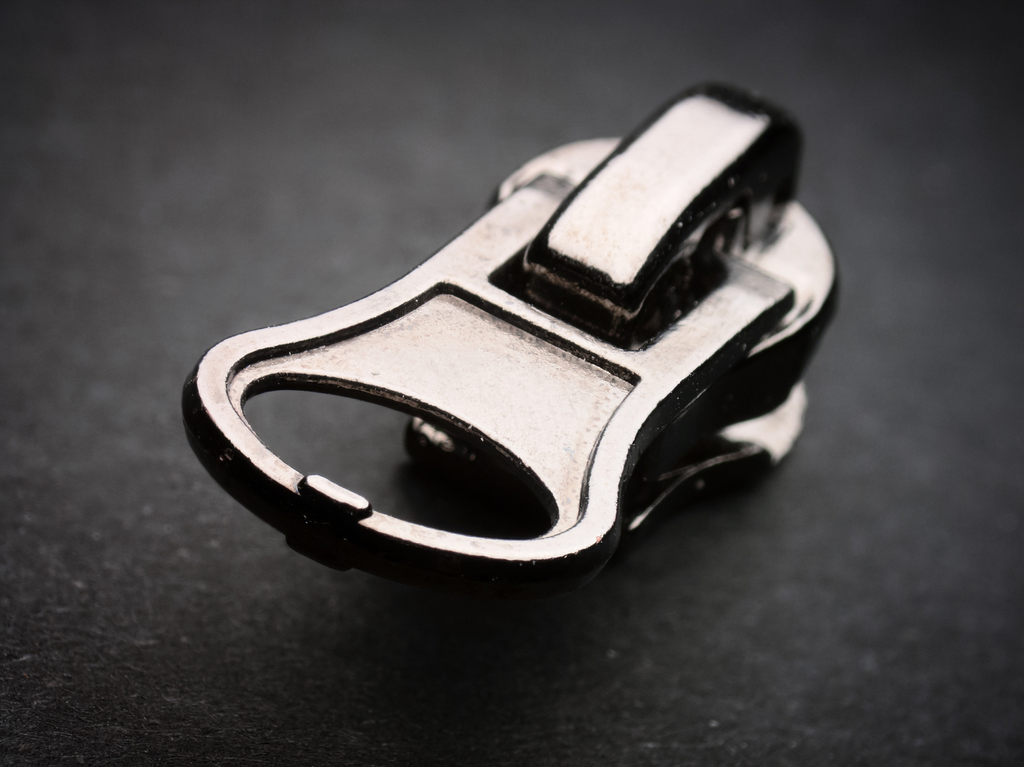 metallic zipper pull on grey background with a vignette