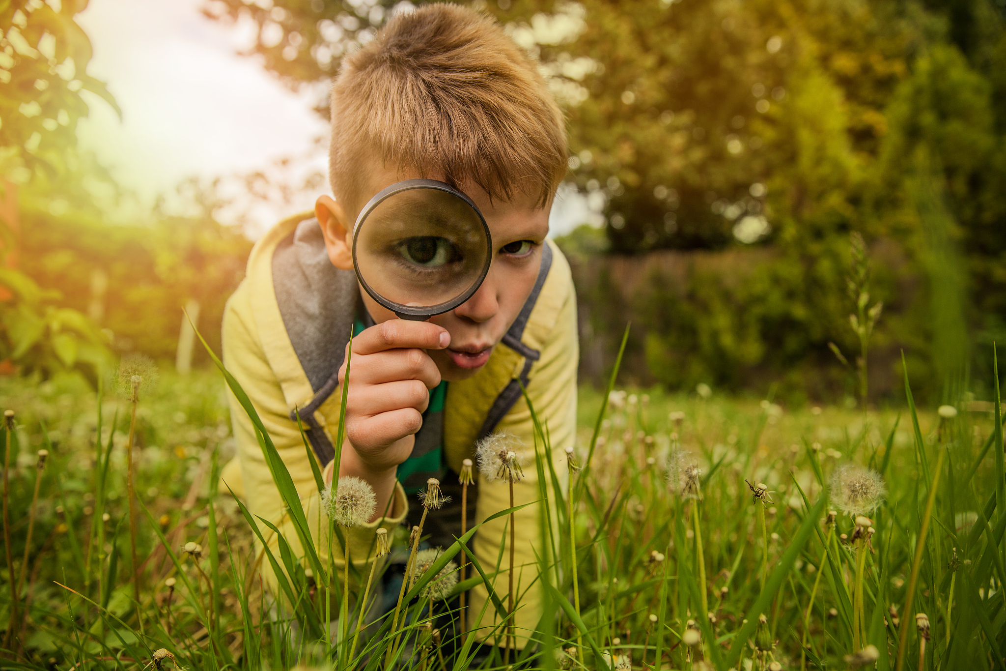 child exploring the outdoors with magnifying glass
