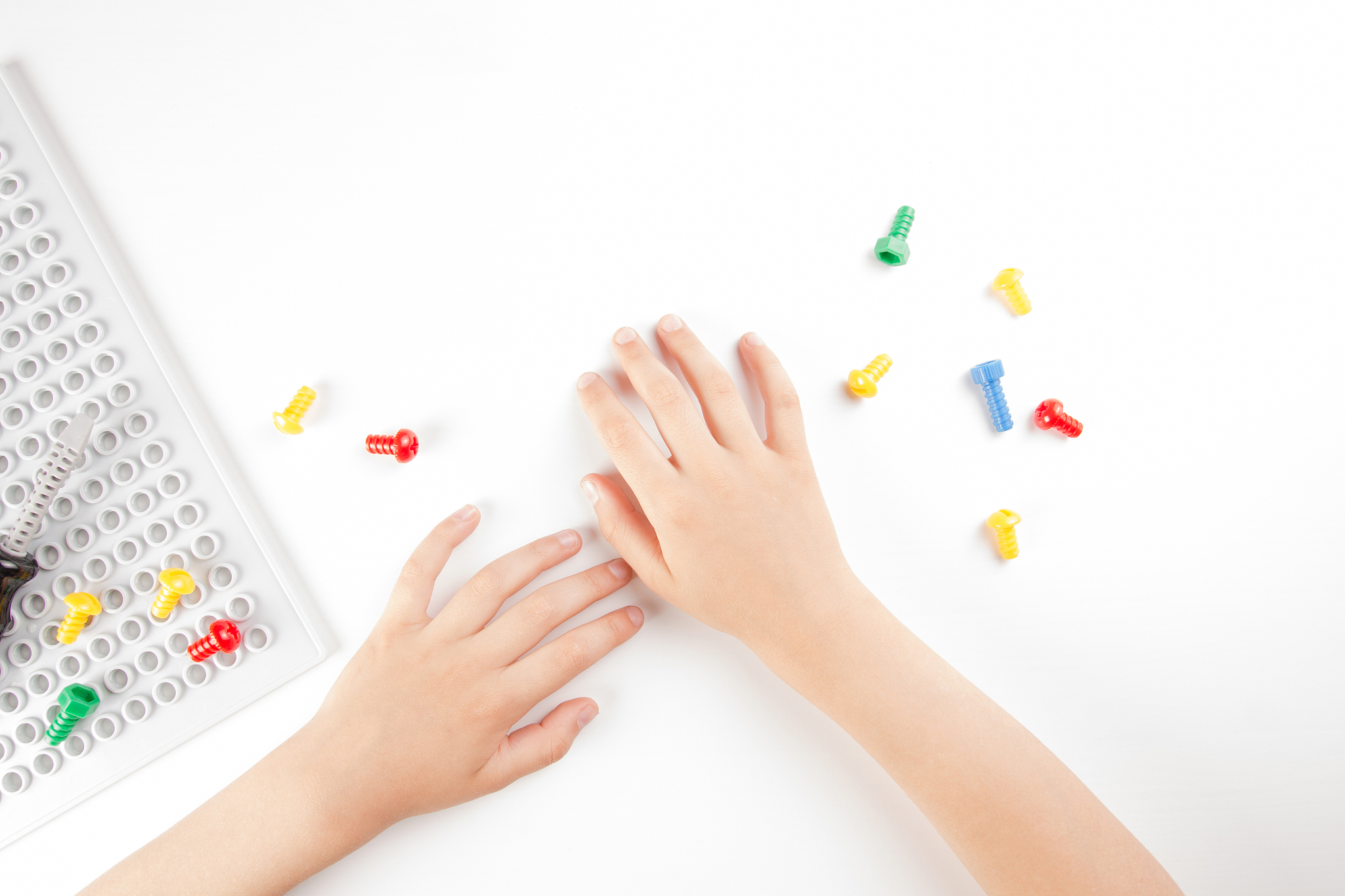 top view on child's hands playing with colorful toys tools on th