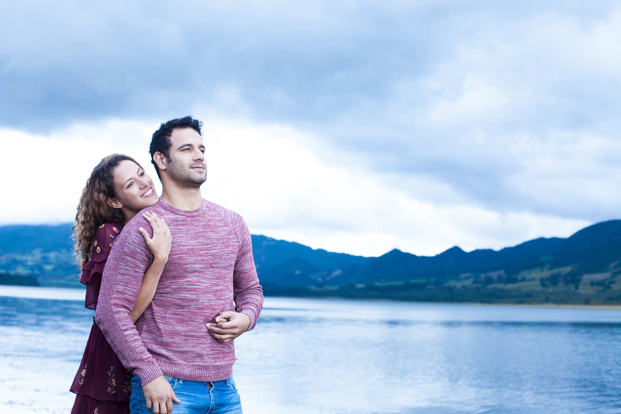 couple in love kissing and hugging beside a lake