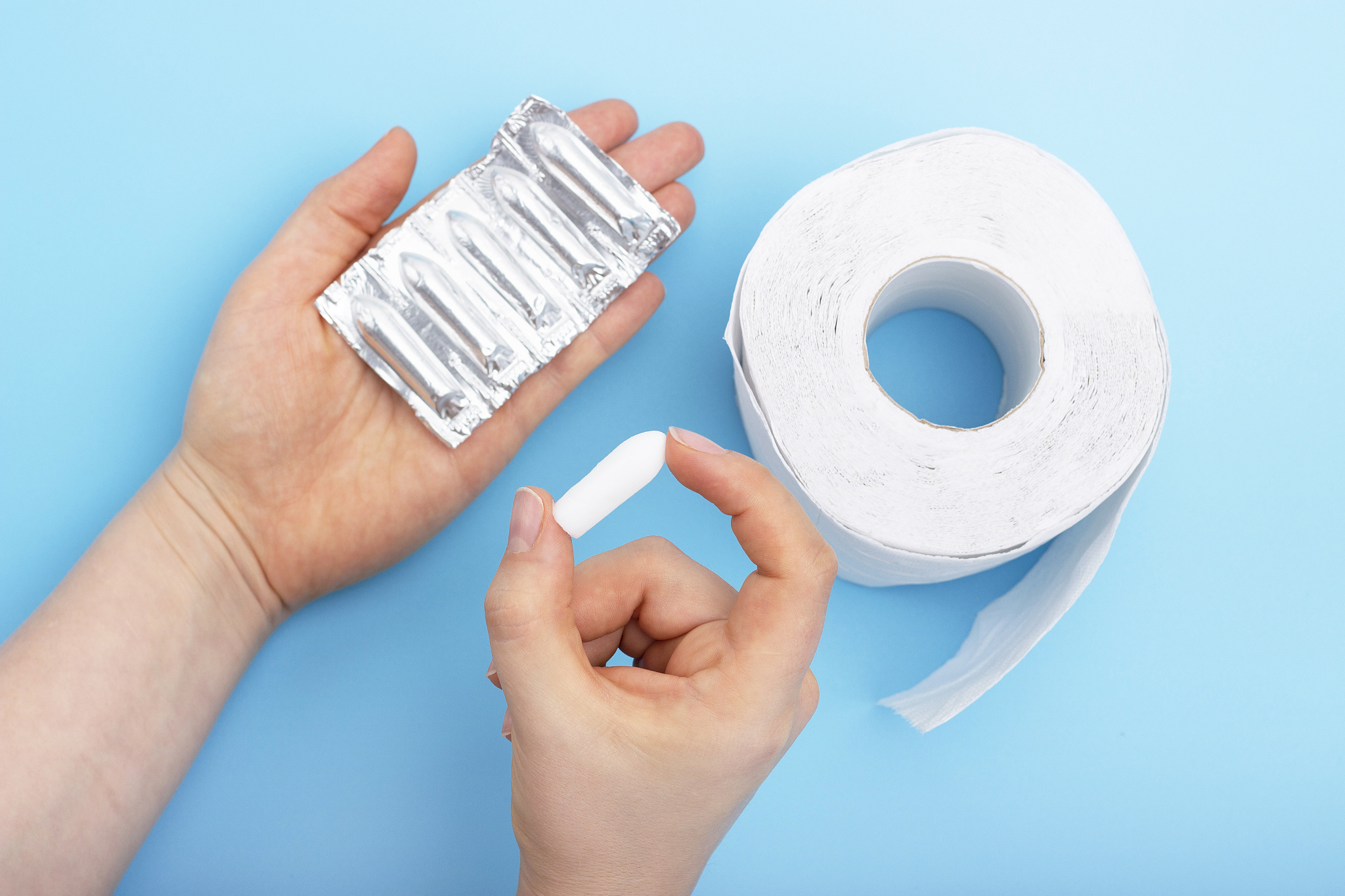 female hand holds suppository on blue background, concept of con