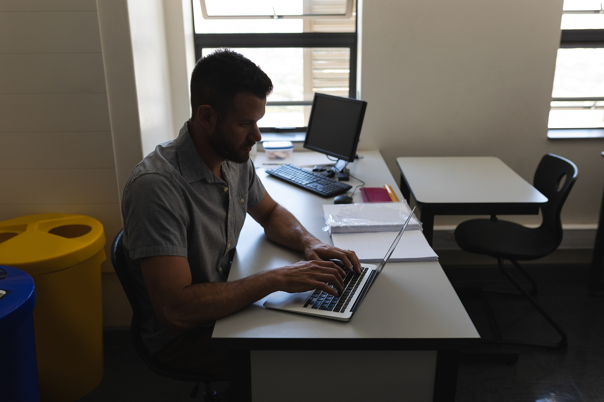 side view of school teacher working on laptop and sitting at des