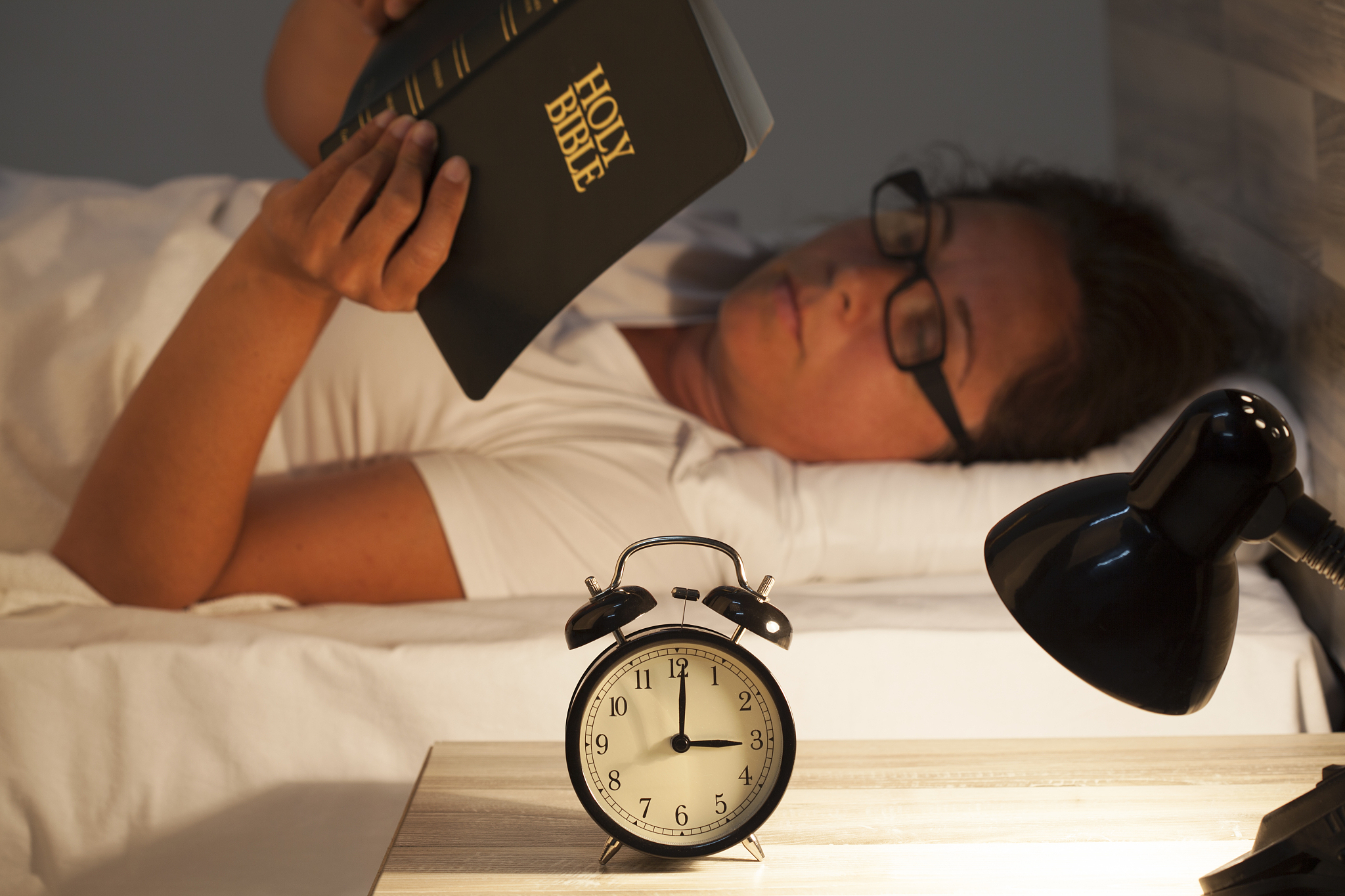 woman lying in bed and reading  bible
